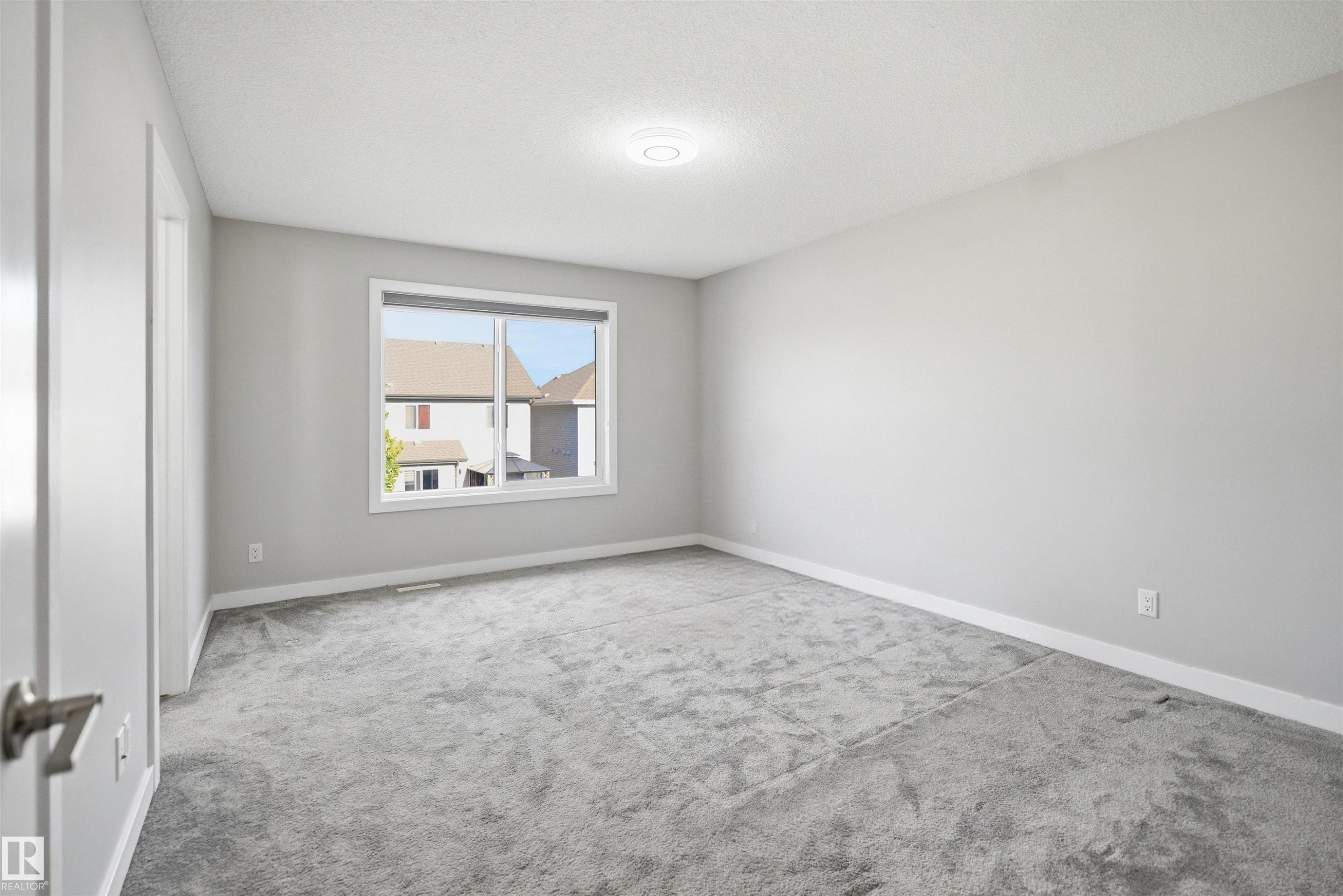 Spacious room featuring light gray walls, gray carpet, a single window, white trim, and a flush-mount ceiling light - 1234 Daniels Crescent, Edmonton, AB - Indoor Photo Showing Other Room
