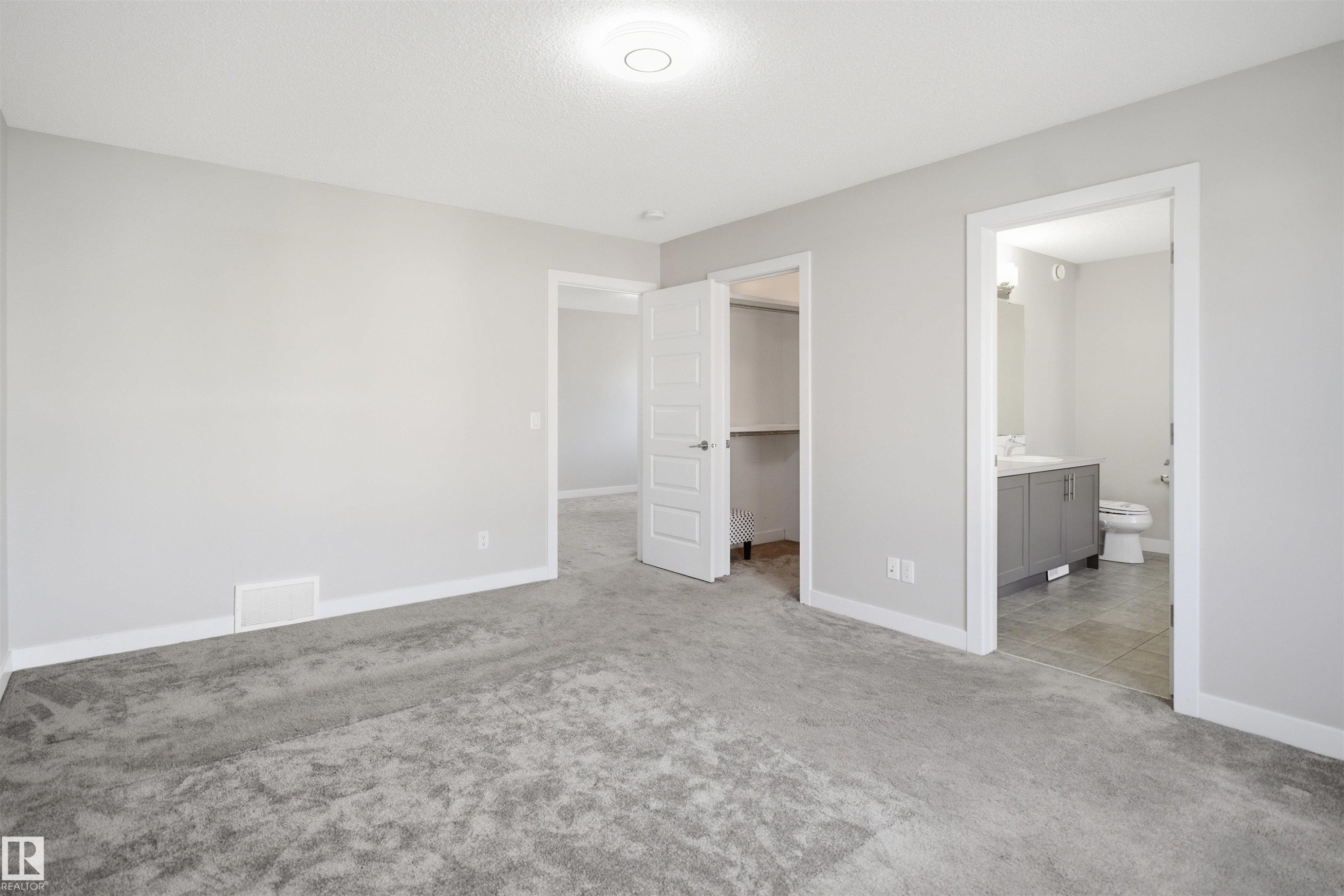 Neutral gray walls with white trim, gray textured carpeting, and a flush mount ceiling light - 1234 Daniels Crescent, Edmonton, AB - Indoor