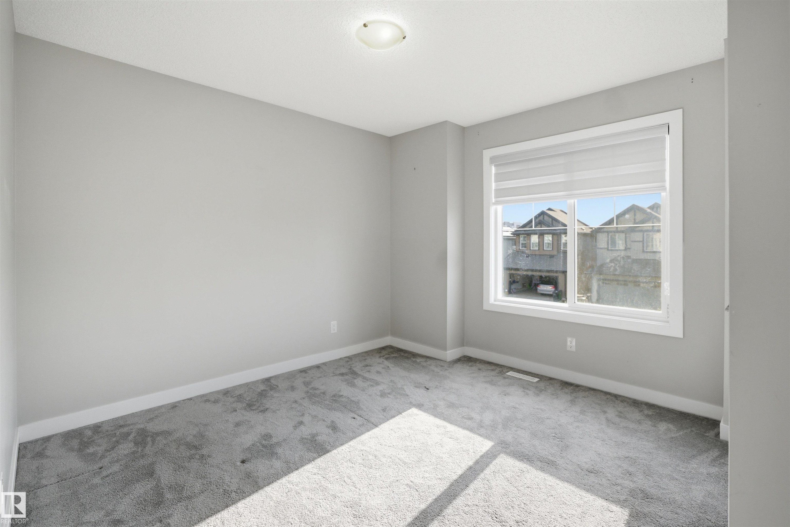 Neutral-toned room featuring a large window with privacy blinds, light gray carpet, and white trim - 1234 Daniels Crescent, Edmonton, AB - Indoor Photo Showing Other Room