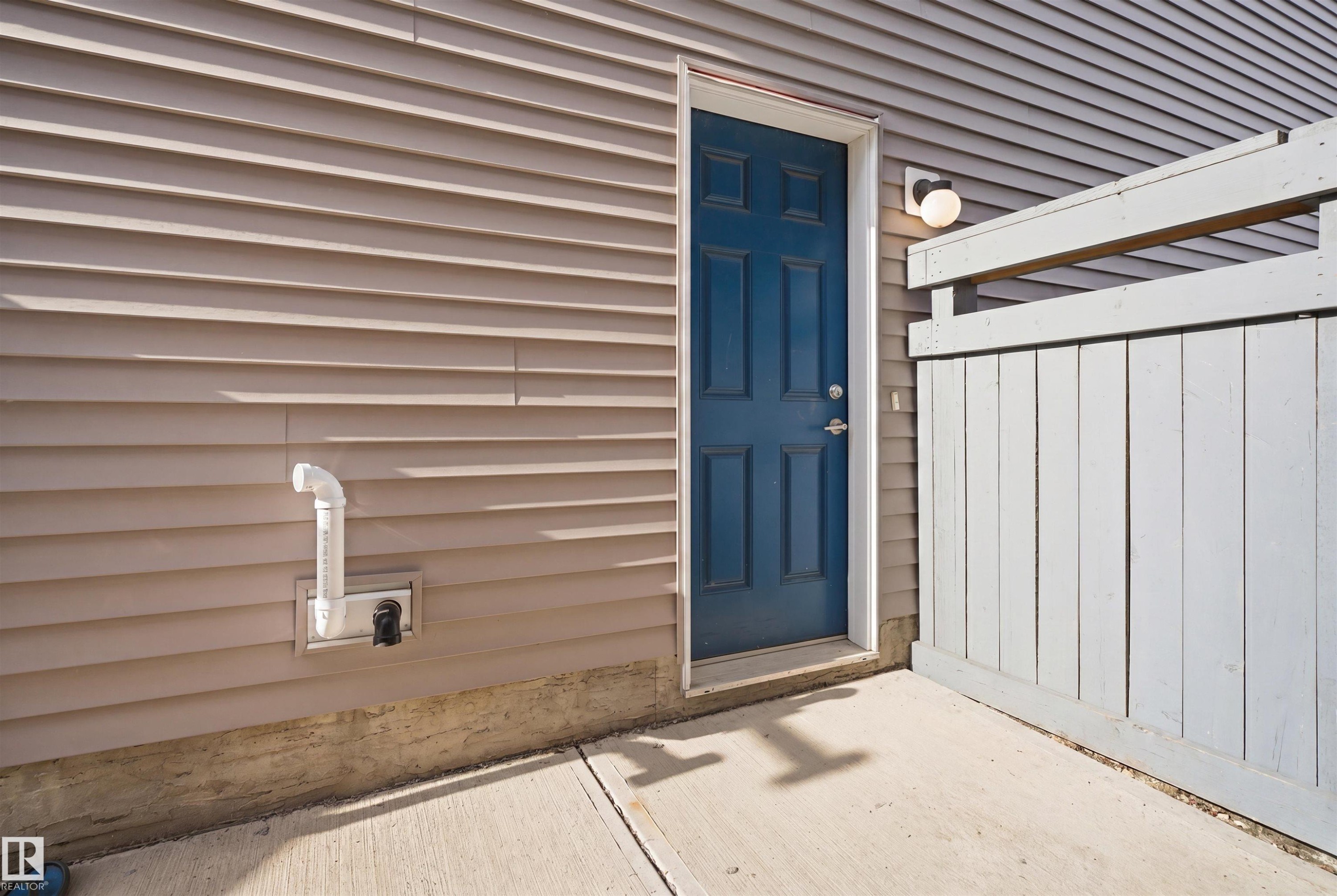 Exterior patio with concrete flooring, framed by a painted wood privacy fence and tan horizontal siding - 1234 Daniels Crescent, Edmonton, AB - Outdoor With Exterior