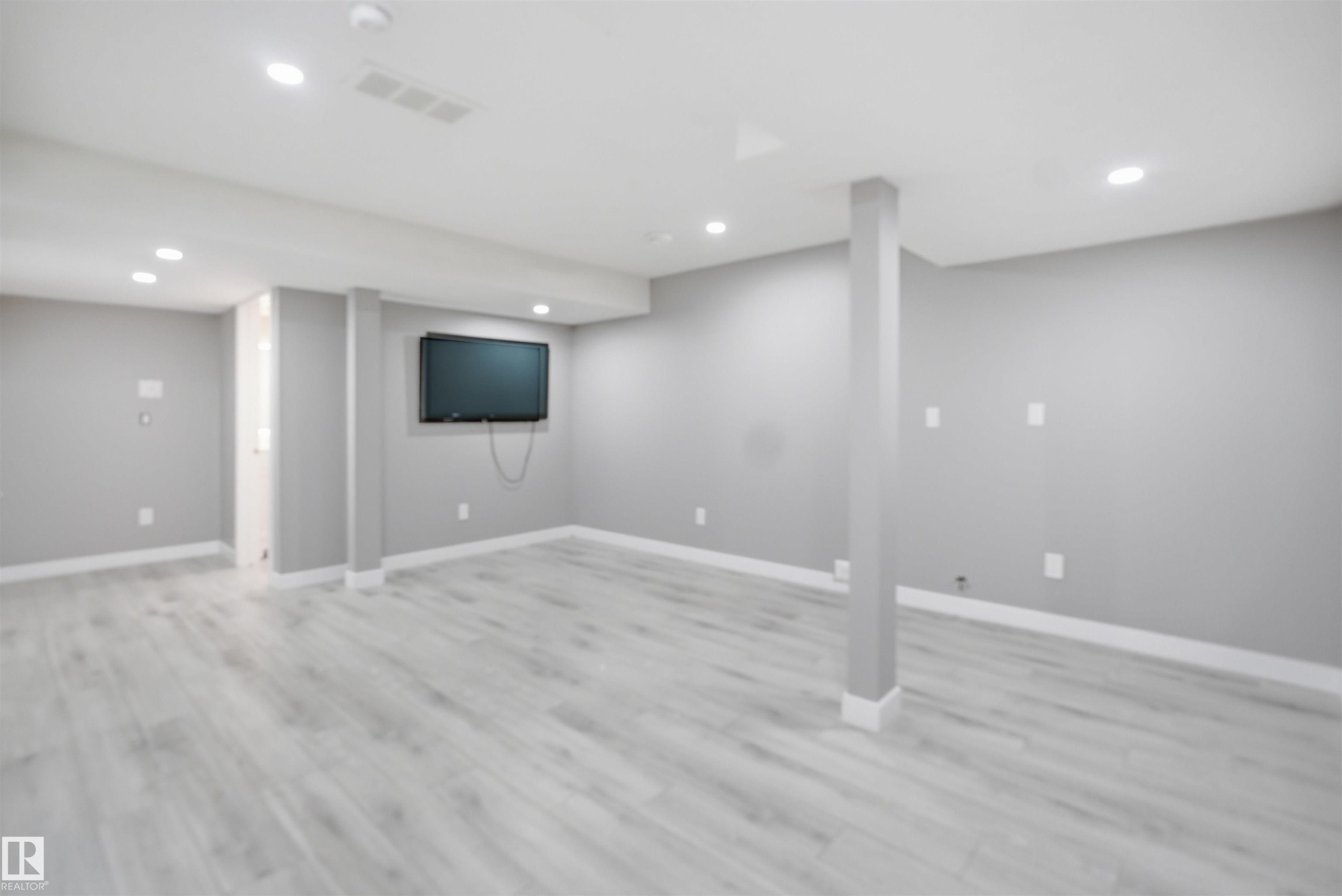 Spacious interior room featuring light-toned wood-finish flooring, recessed lighting, painted walls, and white trim - 1234 Daniels Crescent, Edmonton, AB - Indoor