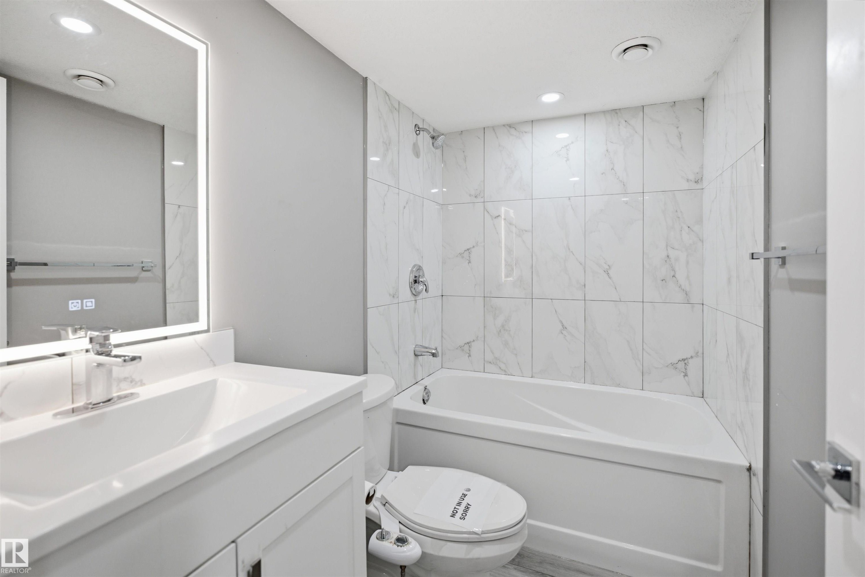 Full bathroom featuring a white vanity with integrated sink, chrome faucet, and an illuminated mirror - 1234 Daniels Crescent, Edmonton, AB - Indoor Photo Showing Bathroom