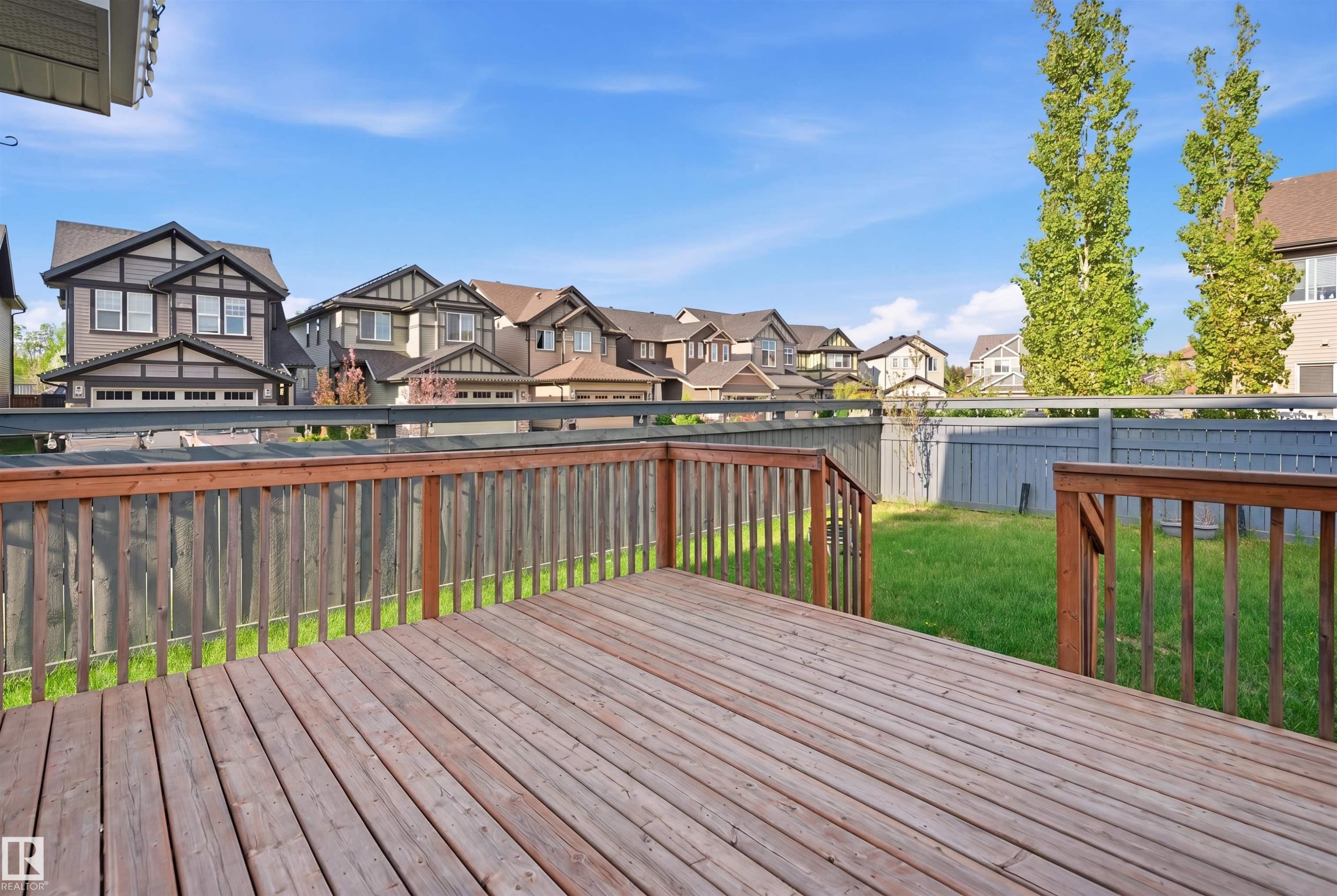 Expansive wood-finish deck with a wooden railing system, overlooking a fenced grassy yard - 1234 Daniels Crescent, Edmonton, AB - Outdoor With Deck Patio Veranda