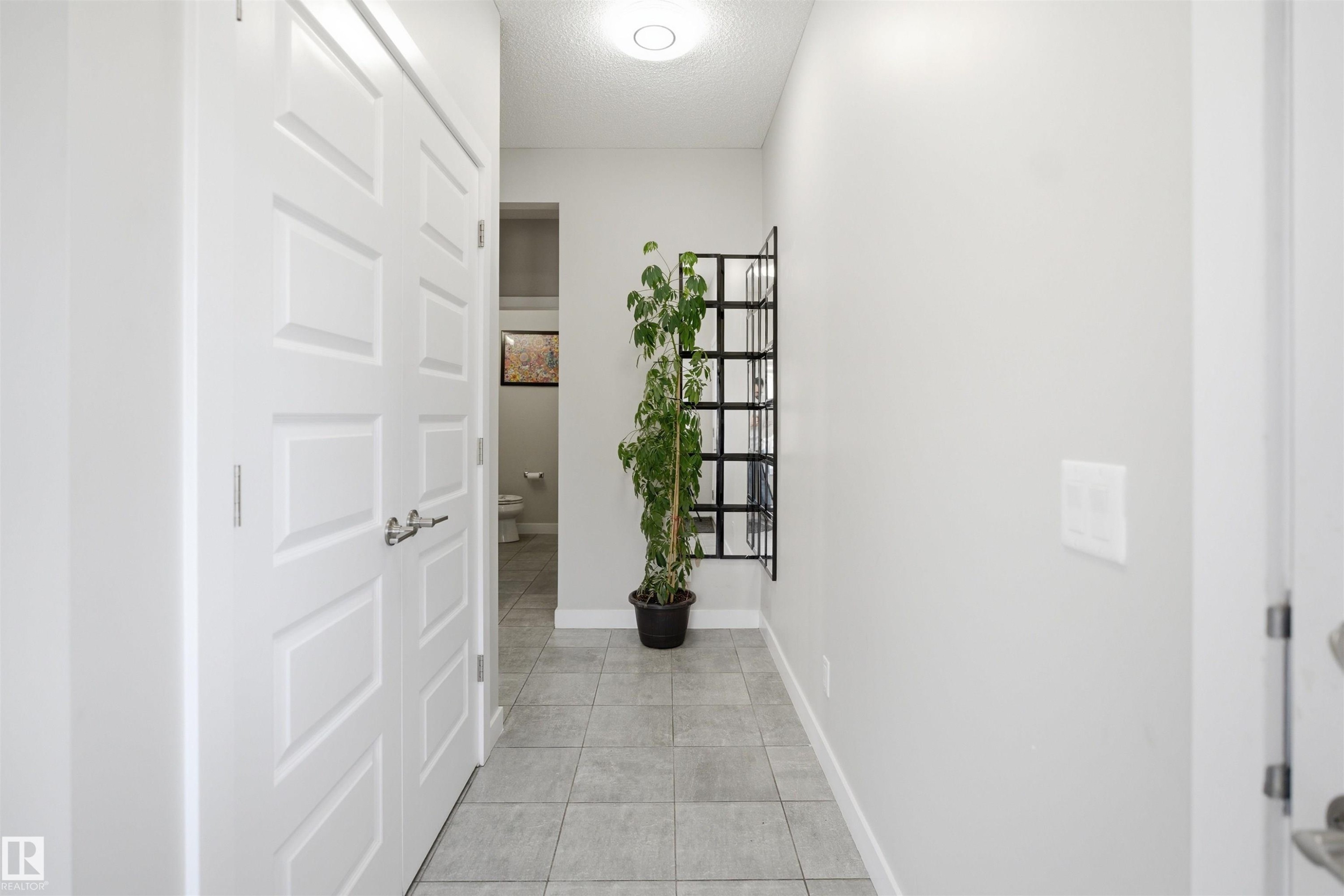 Hallway with light gray tile flooring, white baseboards, and a flush-mount ceiling light fixture - 1234 Daniels Crescent, Edmonton, AB - Indoor Photo Showing Other Room