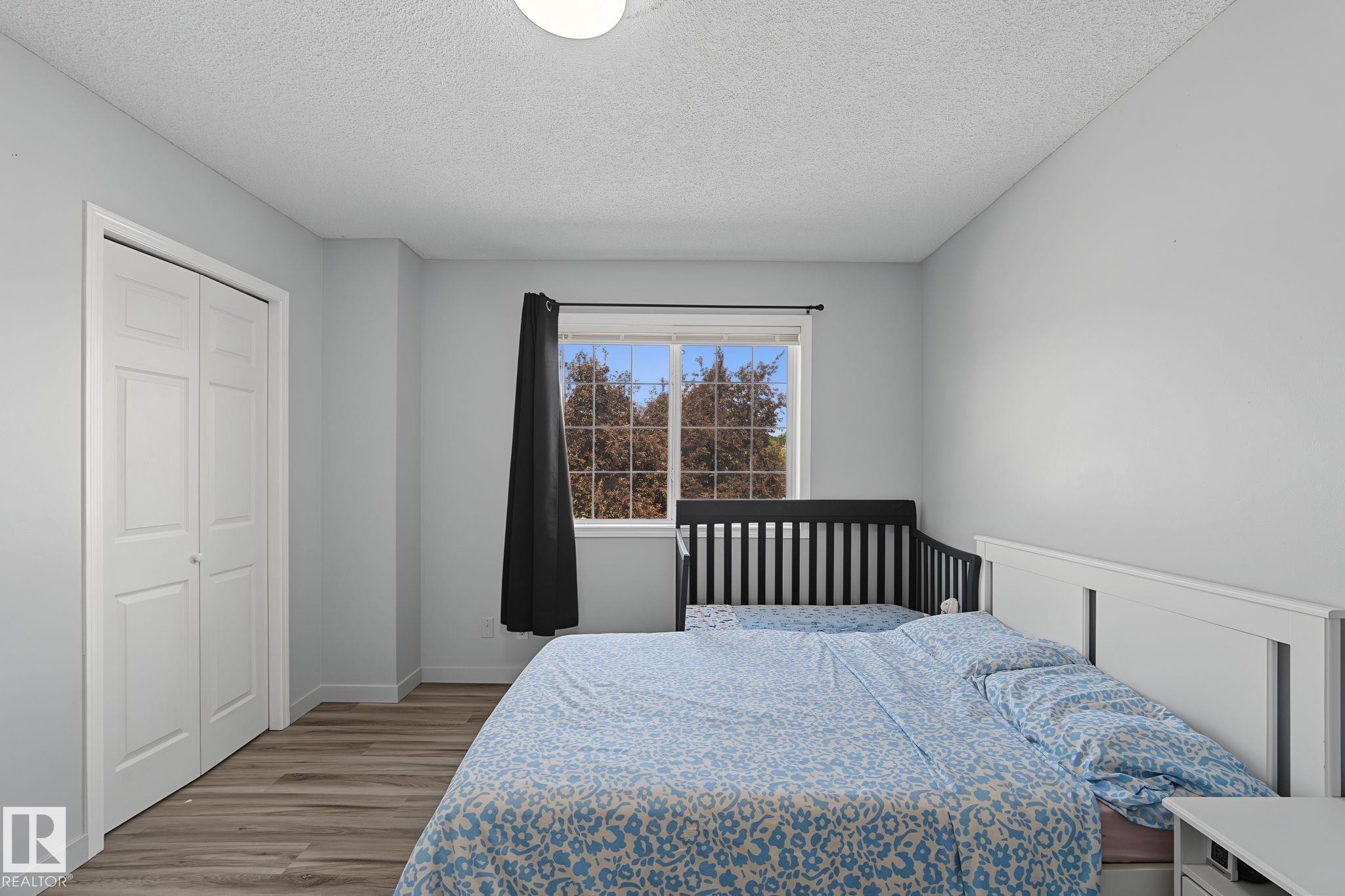 Bedroom featuring light gray walls and wood-finish flooring - 5 14603 Miller Boulevard, Edmonton, AB