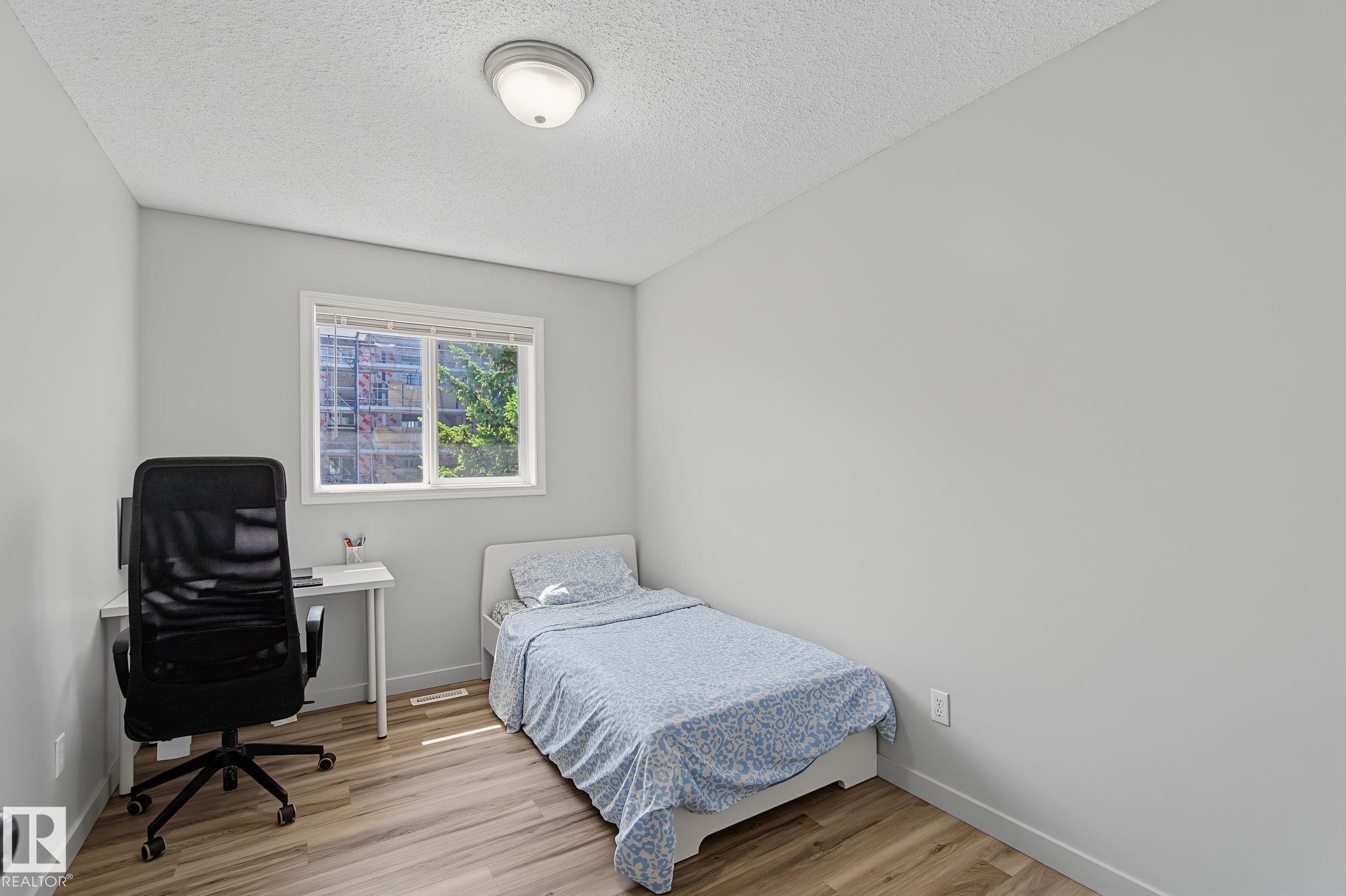 Room featuring a single window, overhead flush-mount lighting, light wood-finish flooring, and neutral wall paint - 5 14603 Miller Boulevard, Edmonton, AB