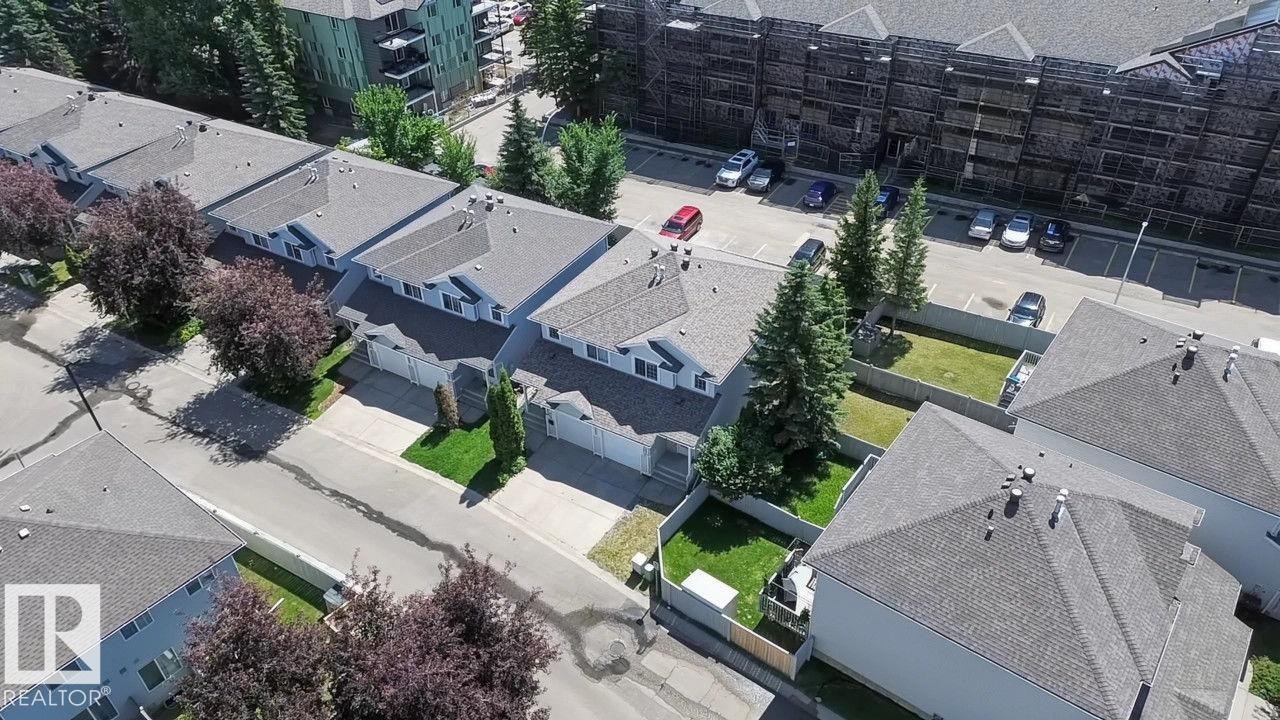 Row of townhomes featuring light-colored siding, attached garages, and gray shingle roofing - 5 14603 Miller Boulevard, Edmonton, AB
