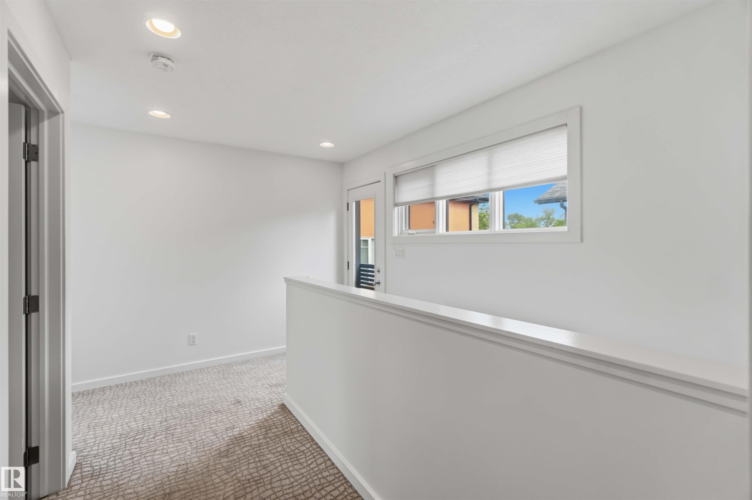Upper-level landing featuring recessed ceiling lighting, a window with blinds, and white painted walls - #1 14315 Stony Plain Nw, Edmonton, AB - Indoor Photo Showing Other Room