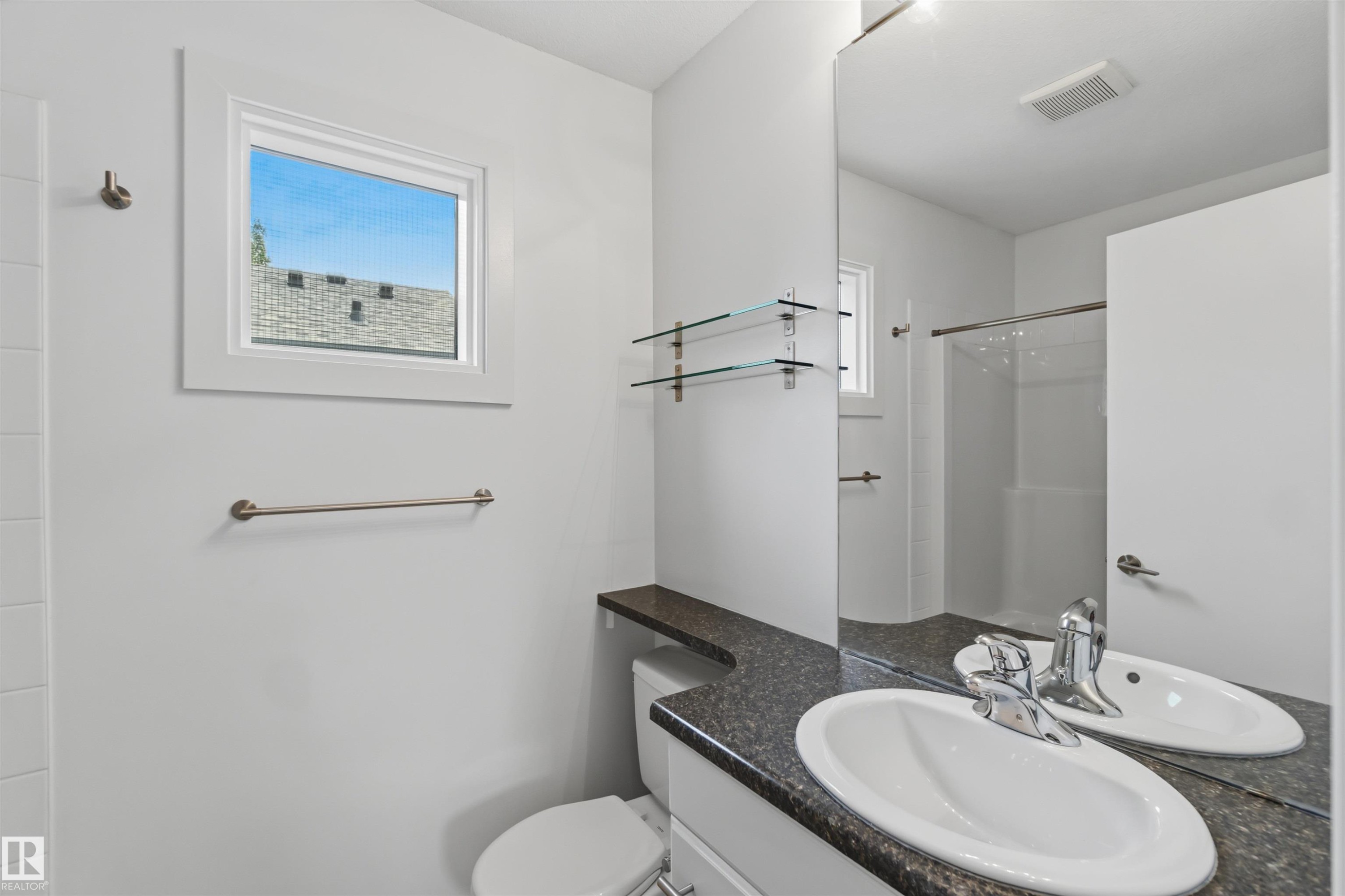 Bathroom featuring a vanity with an oval undermount sink, dark speckled countertop, and a large wall-mounted mirror - #1 14315 Stony Plain Nw, Edmonton, AB - Indoor Photo Showing Bathroom