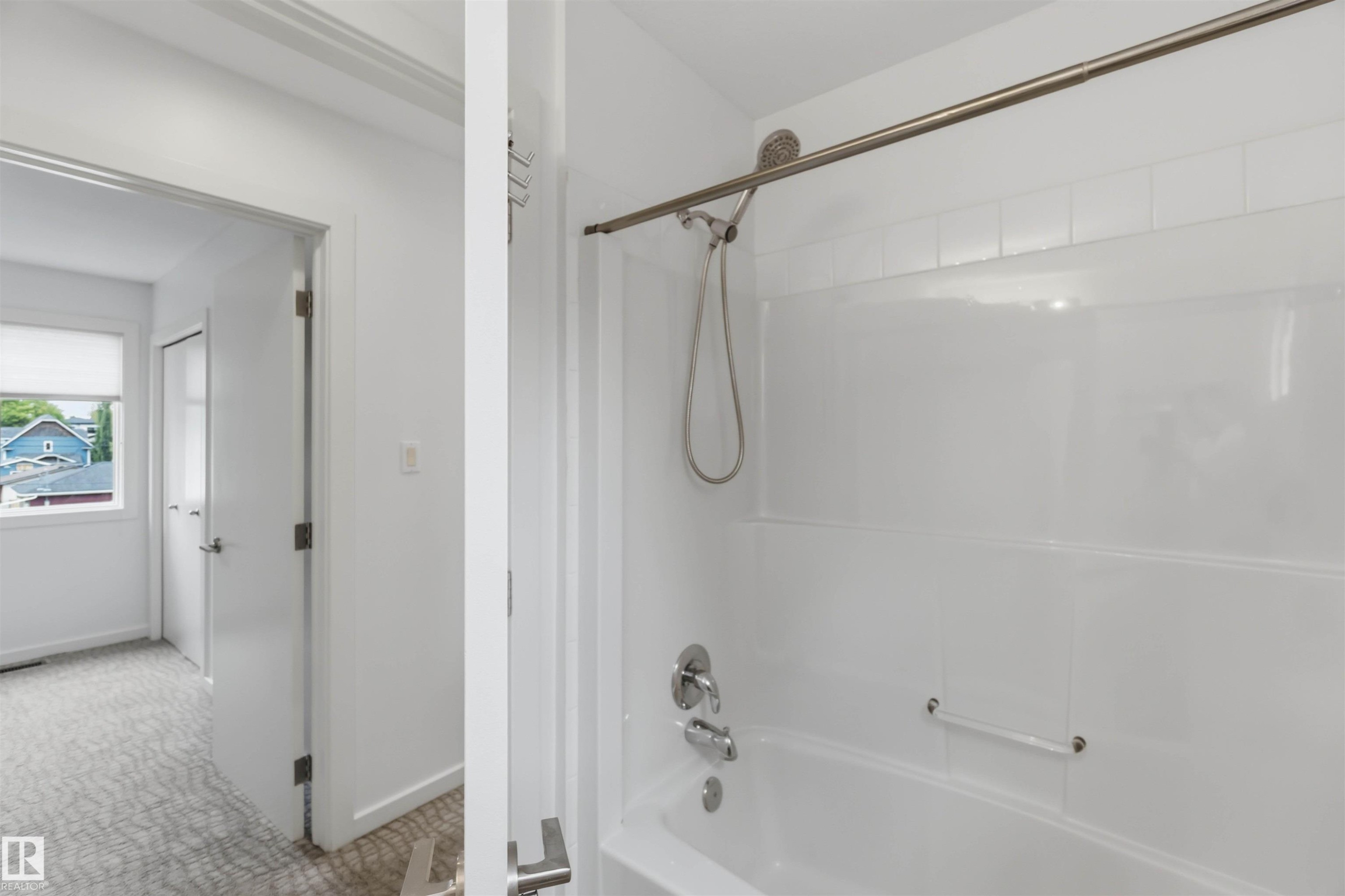 White tub and shower combination with a brushed nickel showerhead and faucet - #1 14315 Stony Plain Nw, Edmonton, AB - Indoor Photo Showing Bathroom