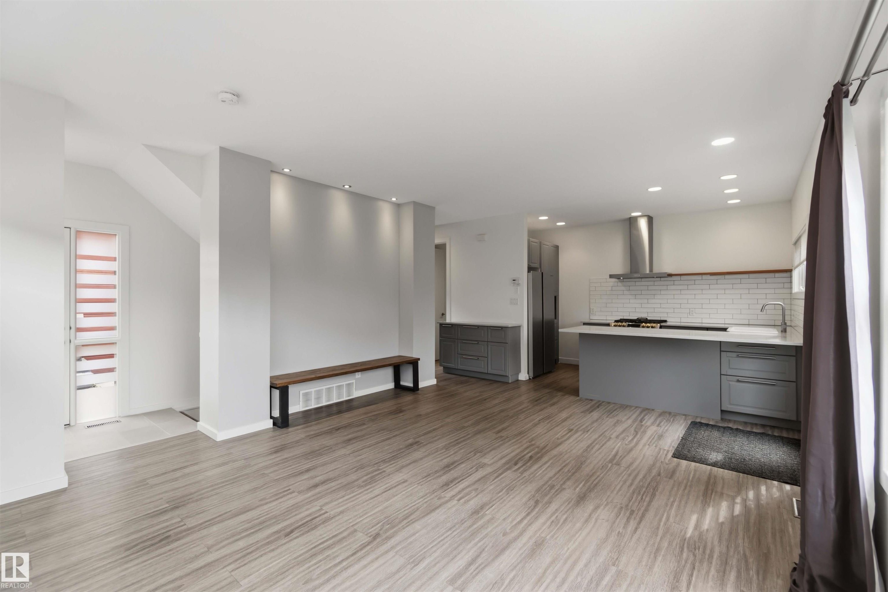 Open-concept living space featuring wood-finish flooring, recessed lighting, and a modern kitchen - #1 14315 Stony Plain Nw, Edmonton, AB - Indoor Photo Showing Kitchen