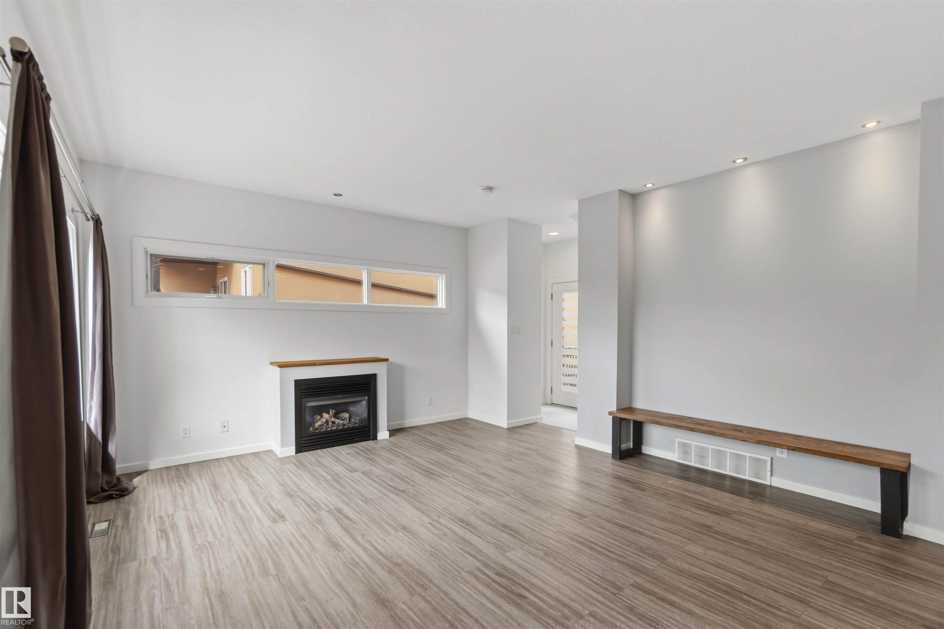 Spacious room featuring wood-finish flooring and recessed lighting - #1 14315 Stony Plain Nw, Edmonton, AB - Indoor With Fireplace