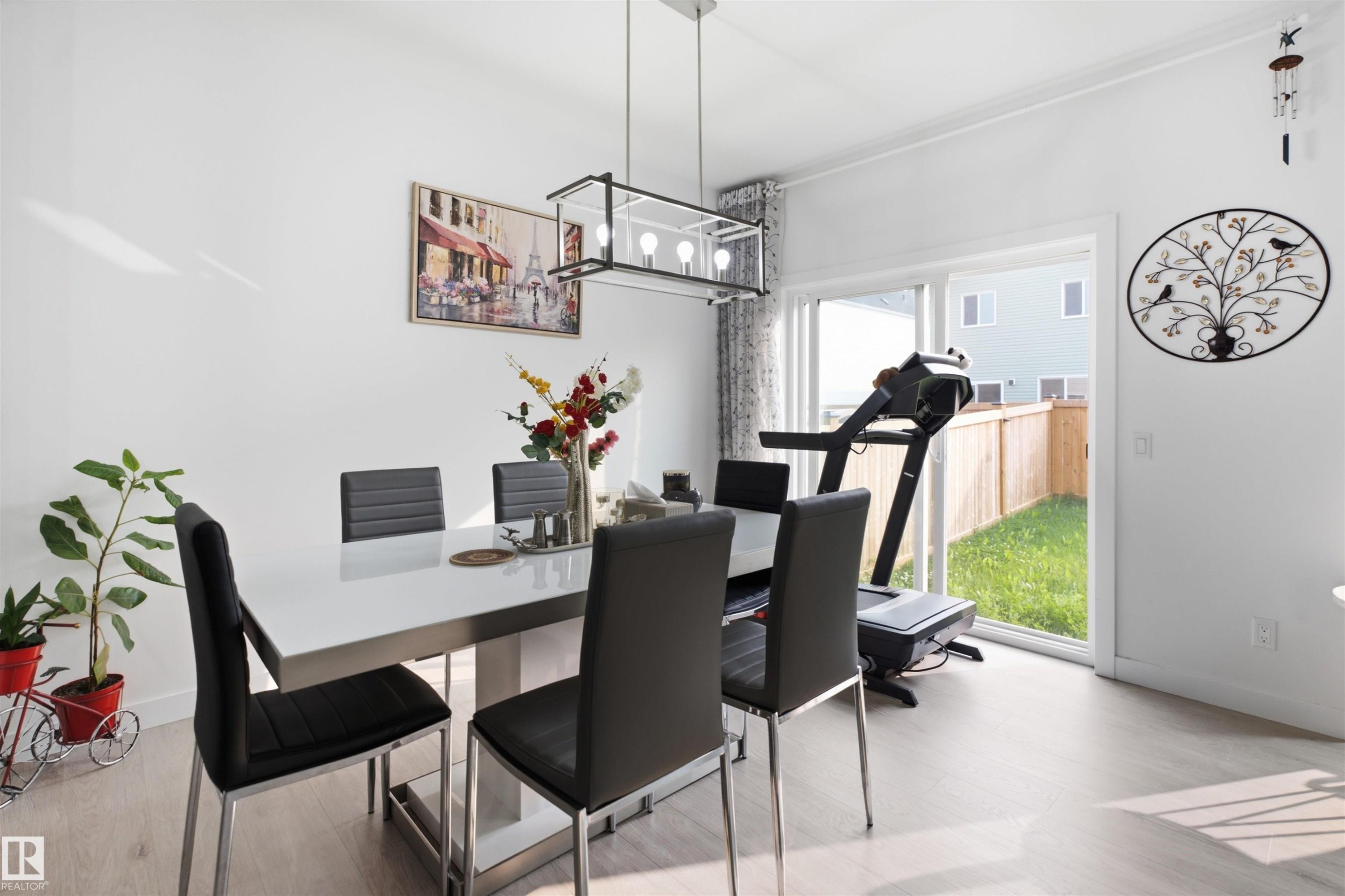 Dining area featuring light wood-finish flooring, white walls, and a contemporary linear chandelier - 2508 193 Street Nw, Edmonton, AB - Indoor Photo Showing Dining Room