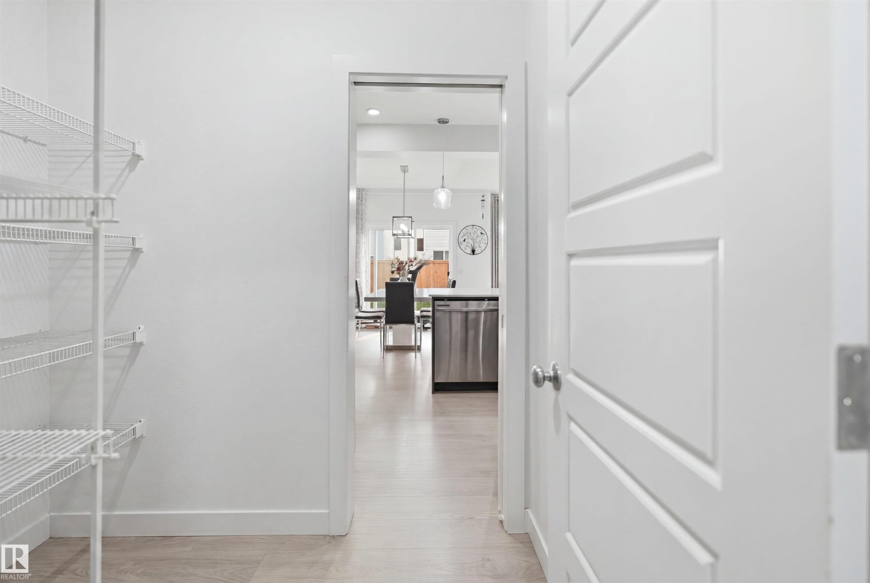 Integrated pantry shelving system with white wire racks, light-toned flooring, and a solid interior door with panel detailing - 2508 193 Street Nw, Edmonton, AB - Indoor With Storage