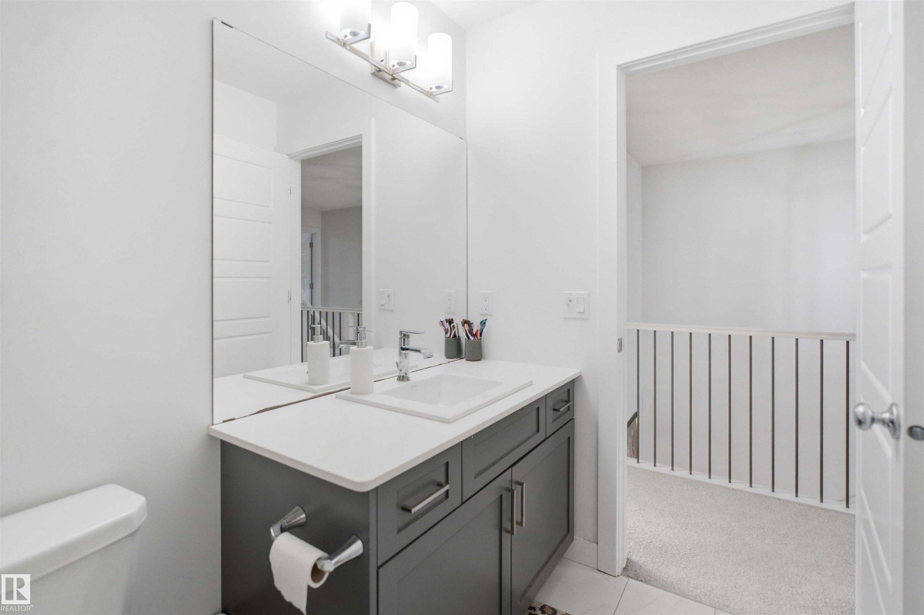 Bathroom featuring a vanity with a white countertop and undermount sink, a chrome faucet, and gray cabinetry with brushed nickel hardware - 2508 193 Street Nw, Edmonton, AB - Indoor Photo Showing Bathroom