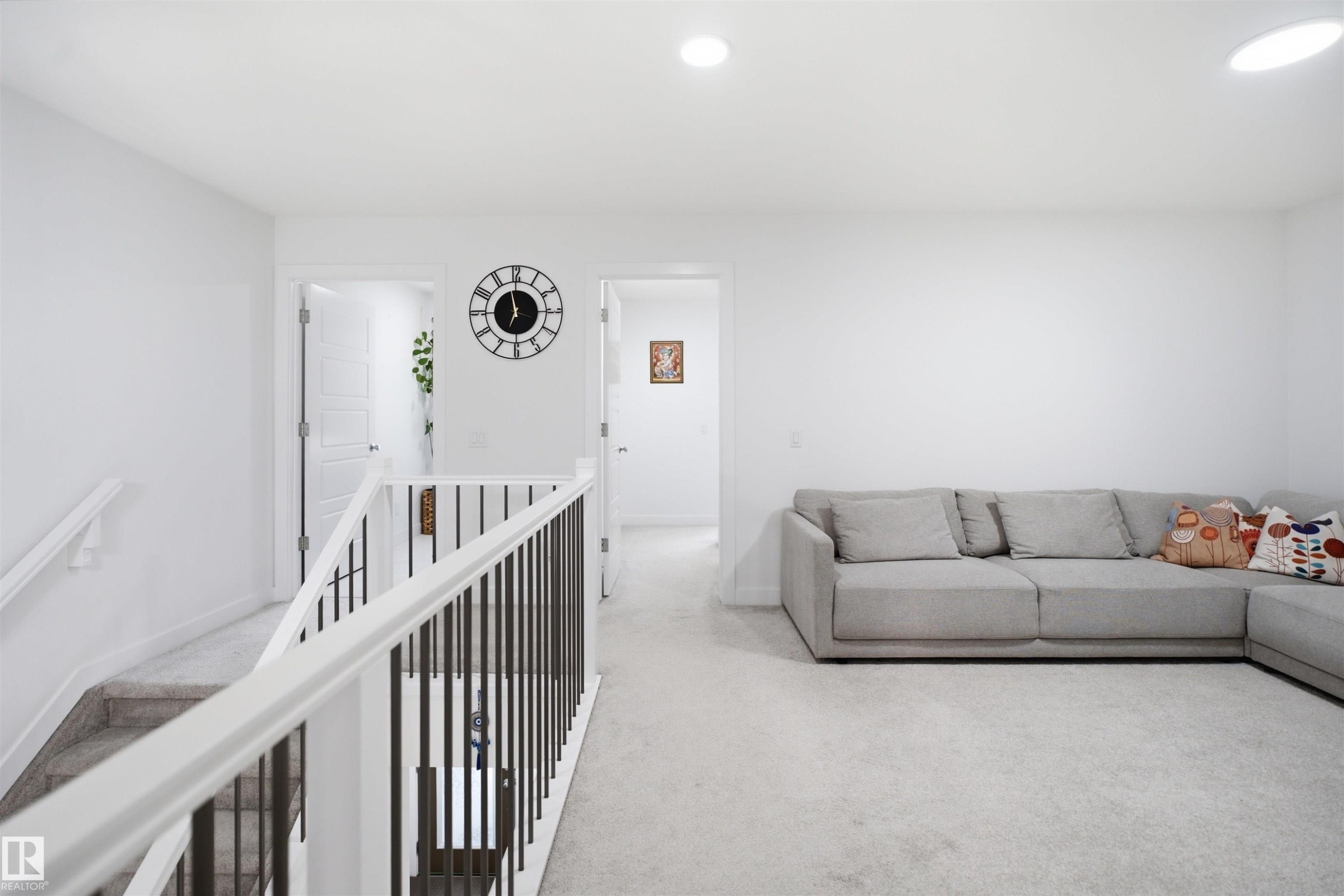 Second-story landing featuring white walls, recessed lighting, carpet flooring, and white banisters with dark metal balusters - 2508 193 Street Nw, Edmonton, AB - Indoor Photo Showing Living Room
