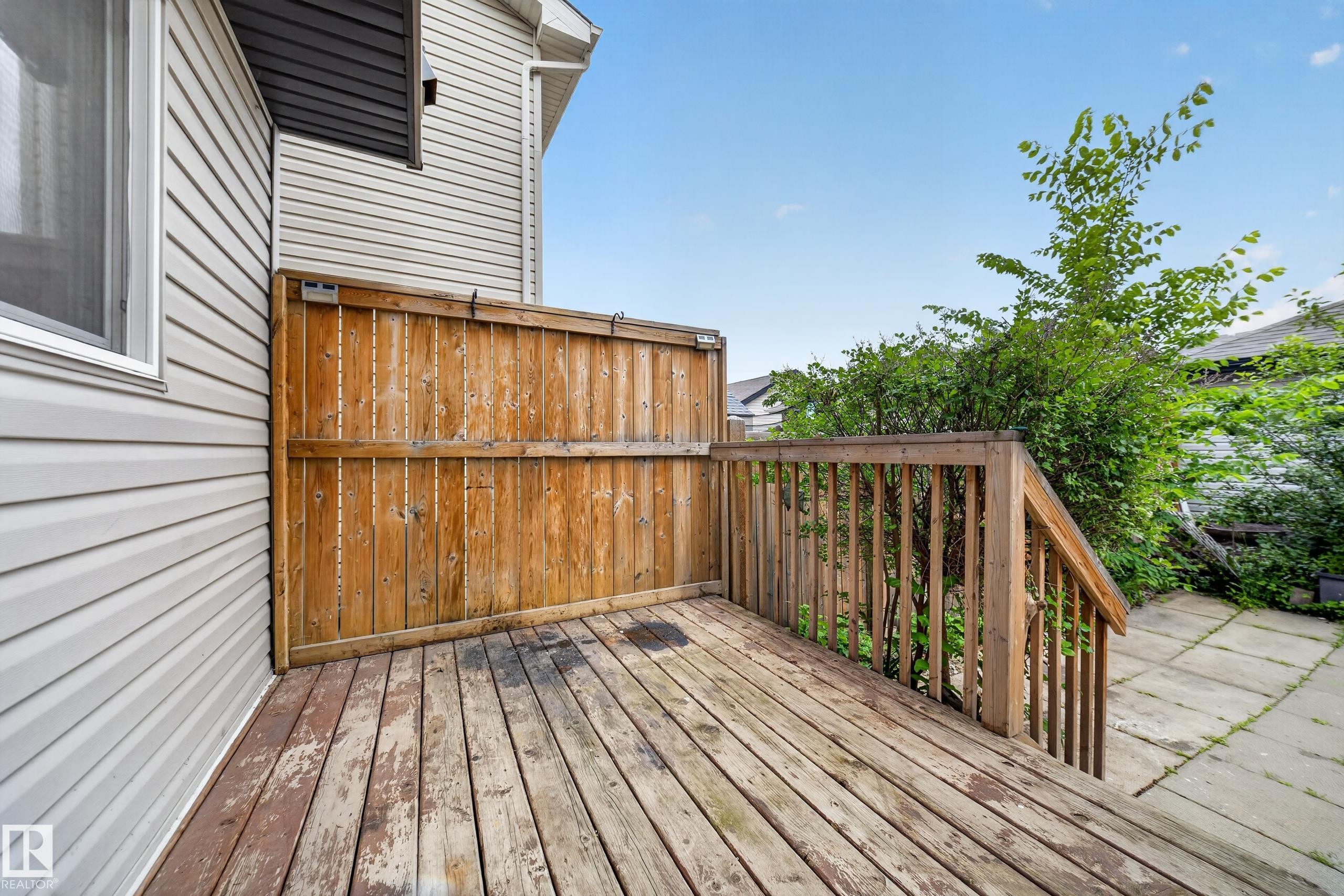 Wood deck with a privacy fence, wood railing, and a patio area - 227 Cy Becker Blvd, Edmonton, AB