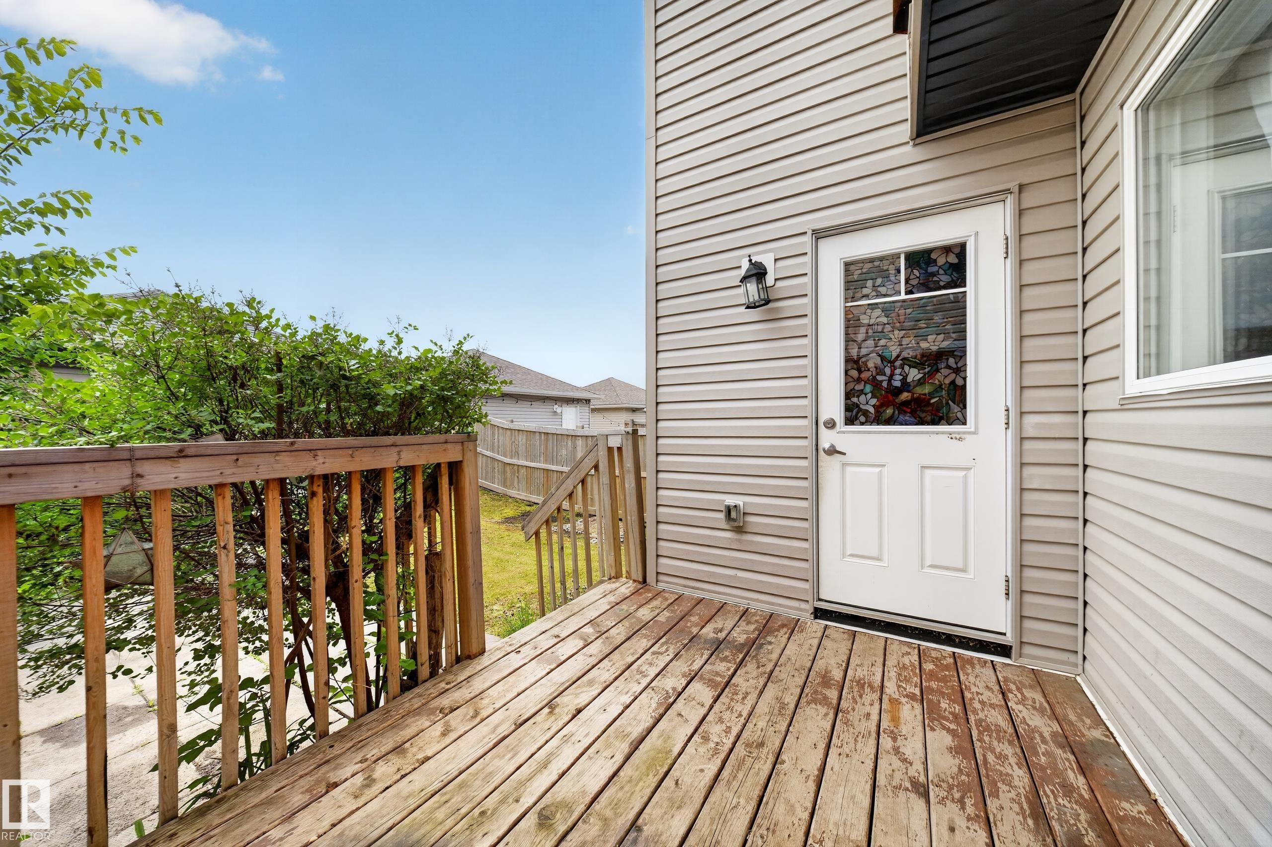 Exterior wood deck featuring a railing and steps to the yard - 227 Cy Becker Blvd, Edmonton, AB