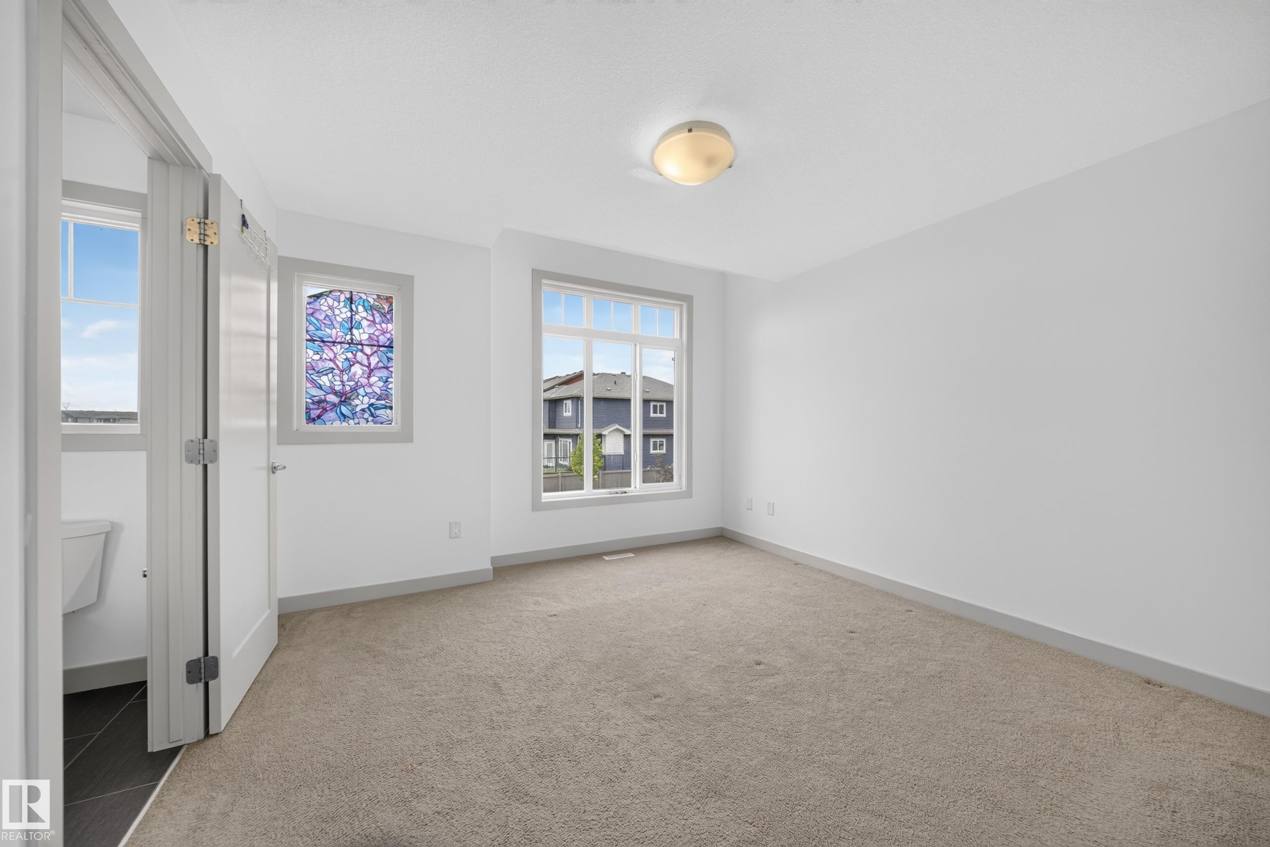 Carpeted room with white walls and a contemporary flush-mount ceiling light fixture - 227 Cy Becker Blvd, Edmonton, AB