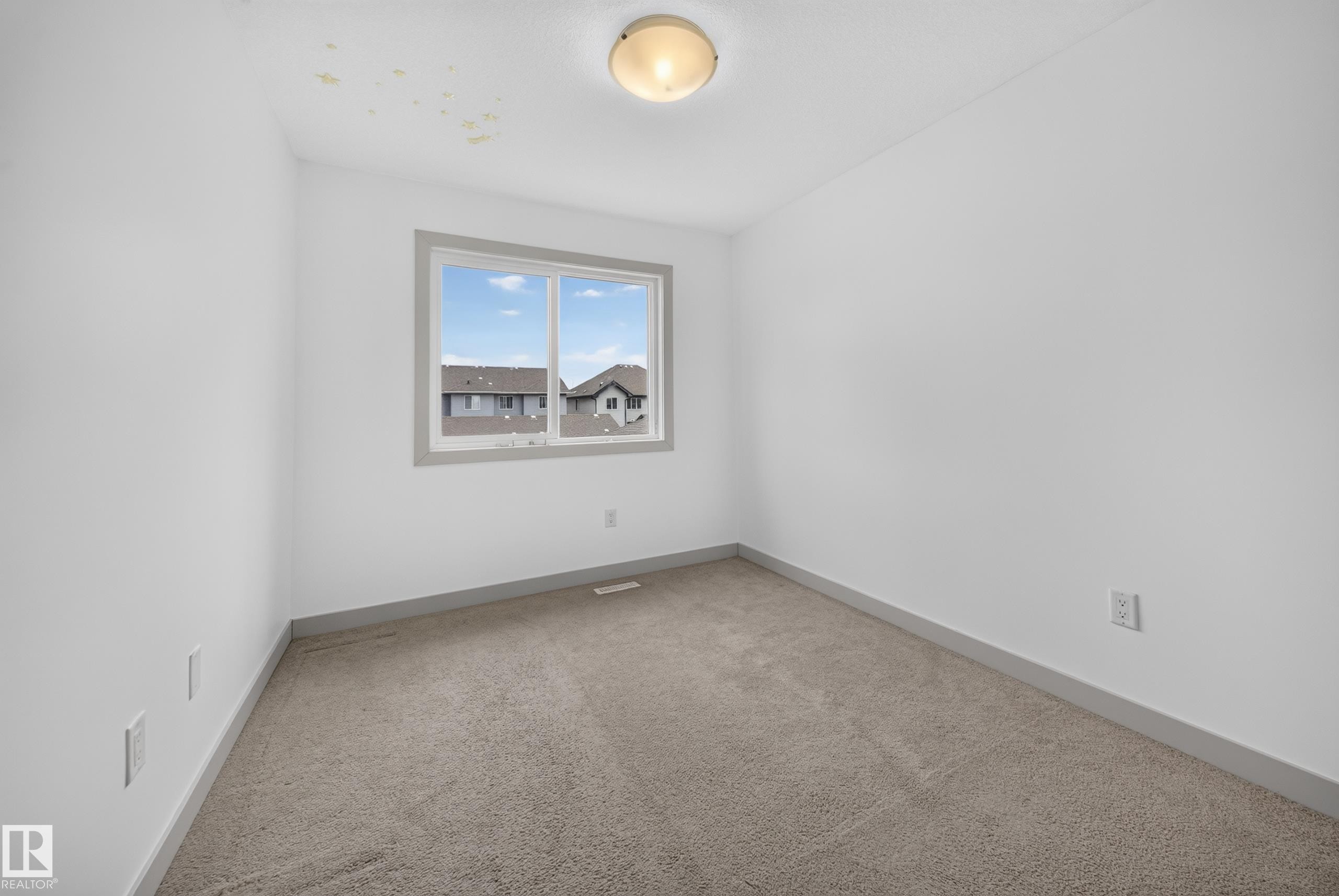Room featuring neutral carpeting, white walls, and a window with gray trim - 227 Cy Becker Blvd, Edmonton, AB