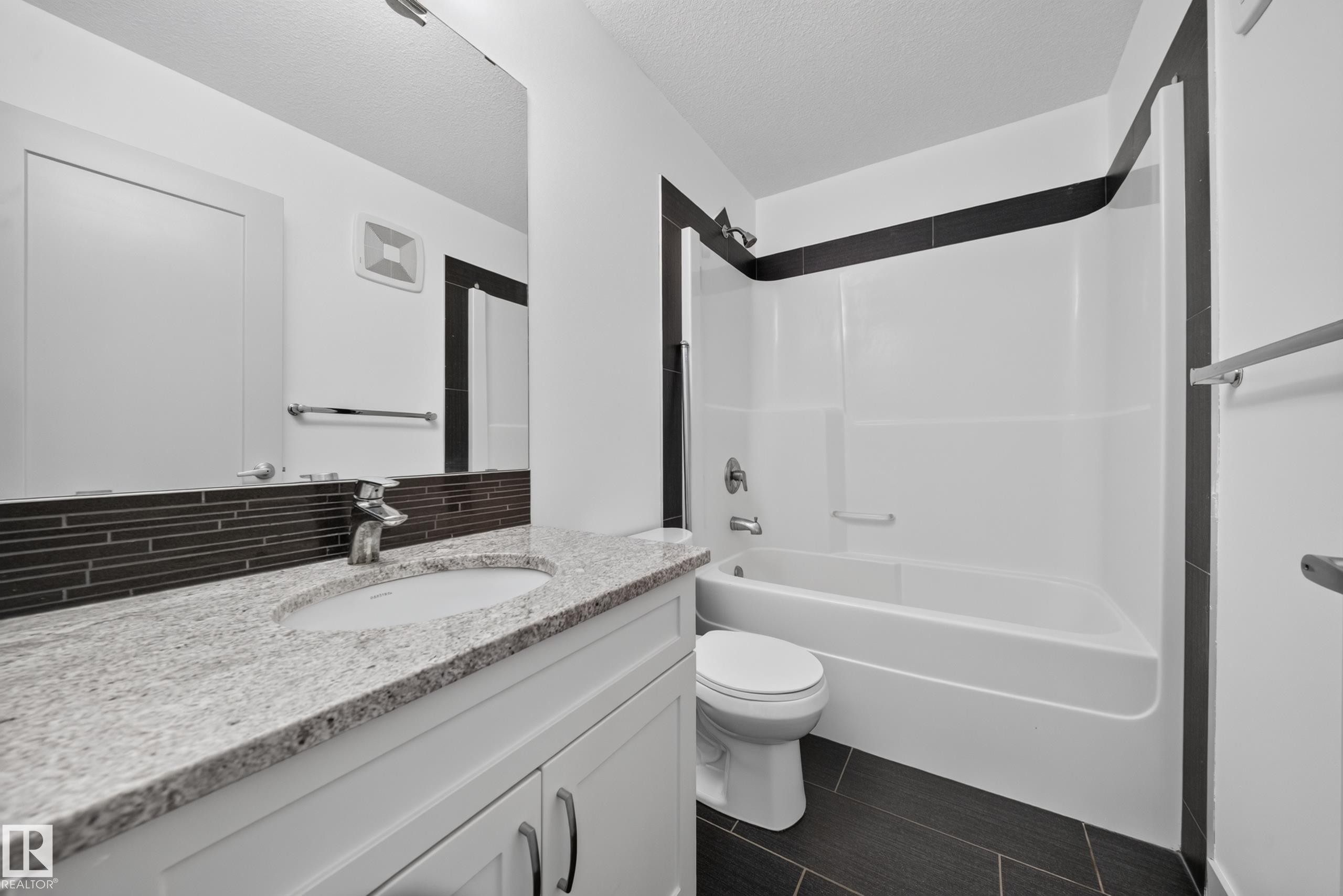 Bathroom featuring a white vanity with granite-finish countertop, integrated sink, and chrome faucet - 227 Cy Becker Blvd, Edmonton, AB