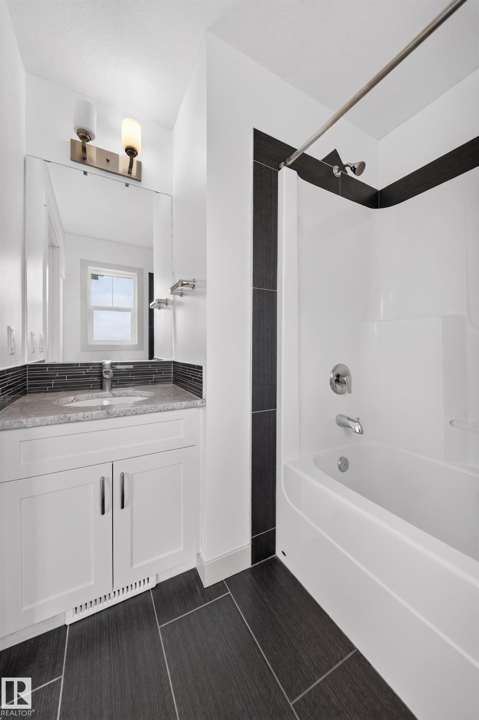 Bathroom featuring a white vanity with granite-finish countertop, undermount sink, and modern brushed nickel hardware - 227 Cy Becker Blvd, Edmonton, AB