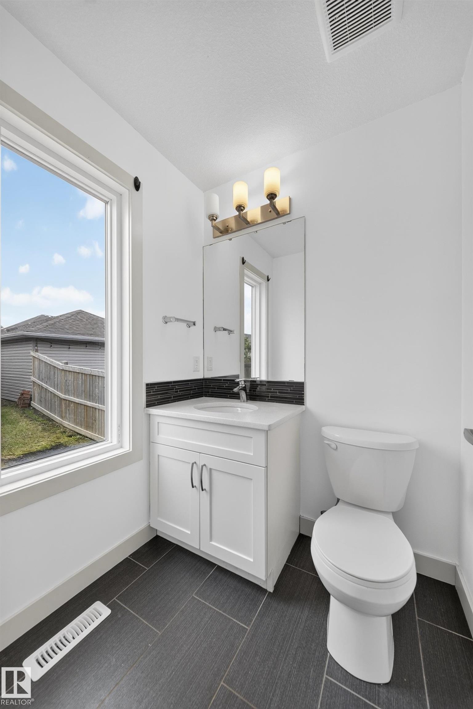 White vanity with integrated sink, chrome faucet, and dark tile backsplash - 227 Cy Becker Blvd, Edmonton, AB
