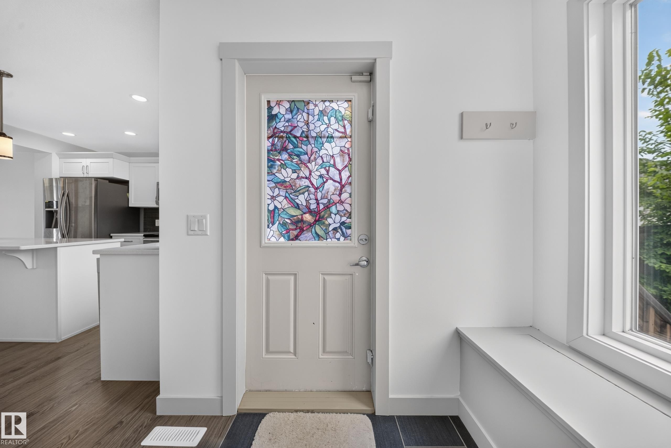 Entryway featuring a decorative stained-glass panel door, built-in window bench, and dark tile flooring - 227 Cy Becker Blvd, Edmonton, AB