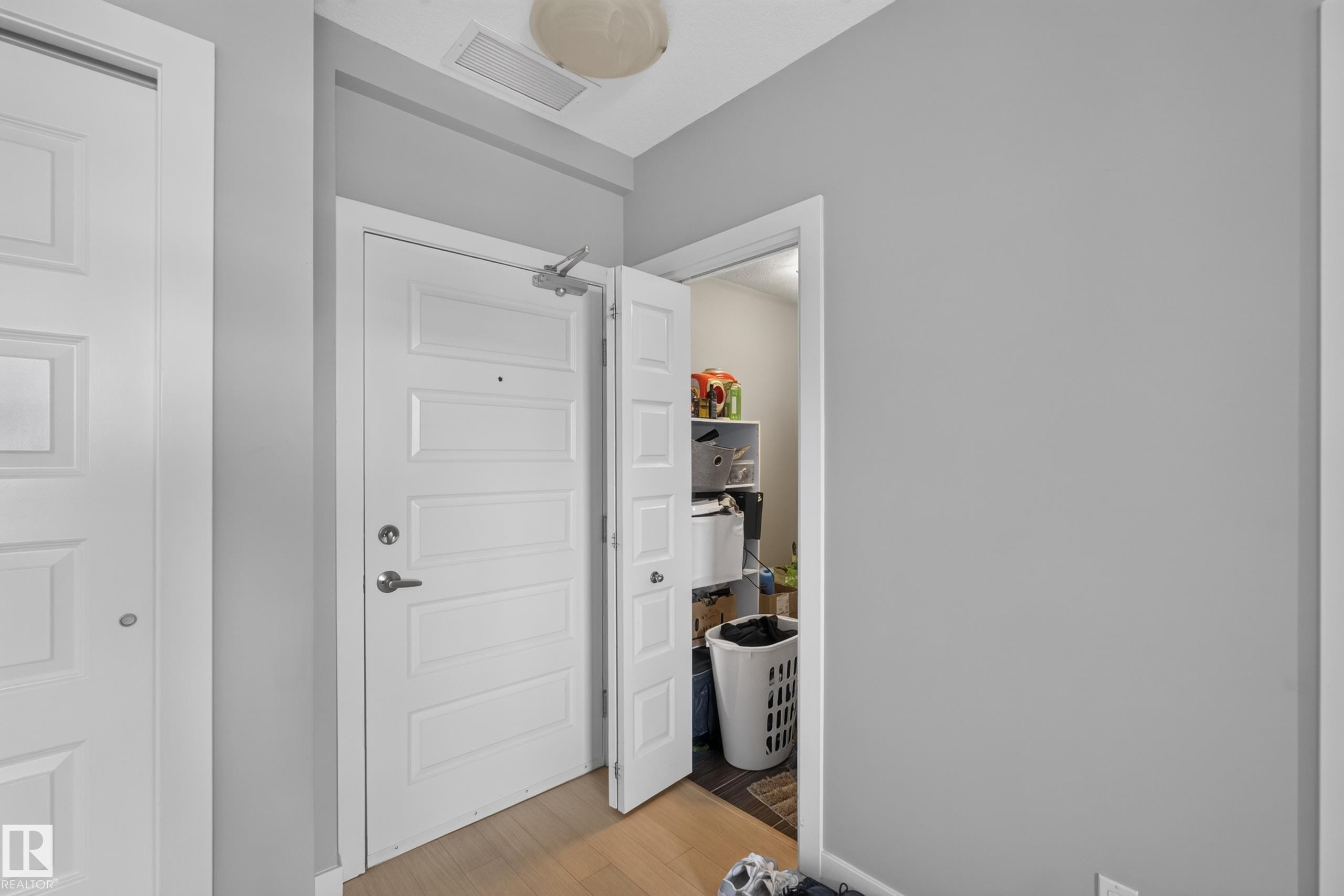 Entryway featuring light wood-finish flooring, two white paneled doors, and a recessed ceiling light - 706 5151 Windermere Boulevard, Edmonton, AB