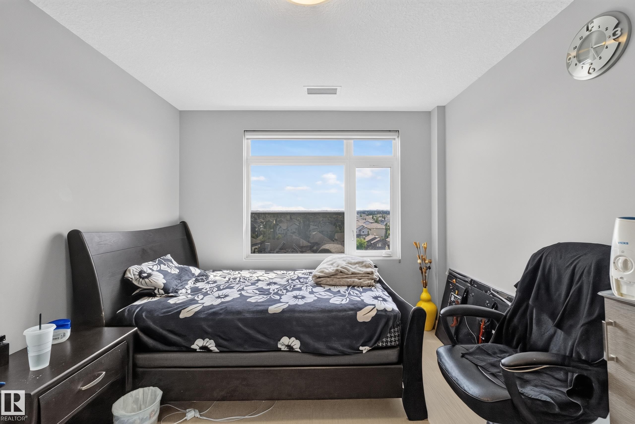 Bright room featuring light gray walls, a window with a distant landscape, light wood-finish flooring, and a ceiling light fixture - 706 5151 Windermere Boulevard, Edmonton, AB