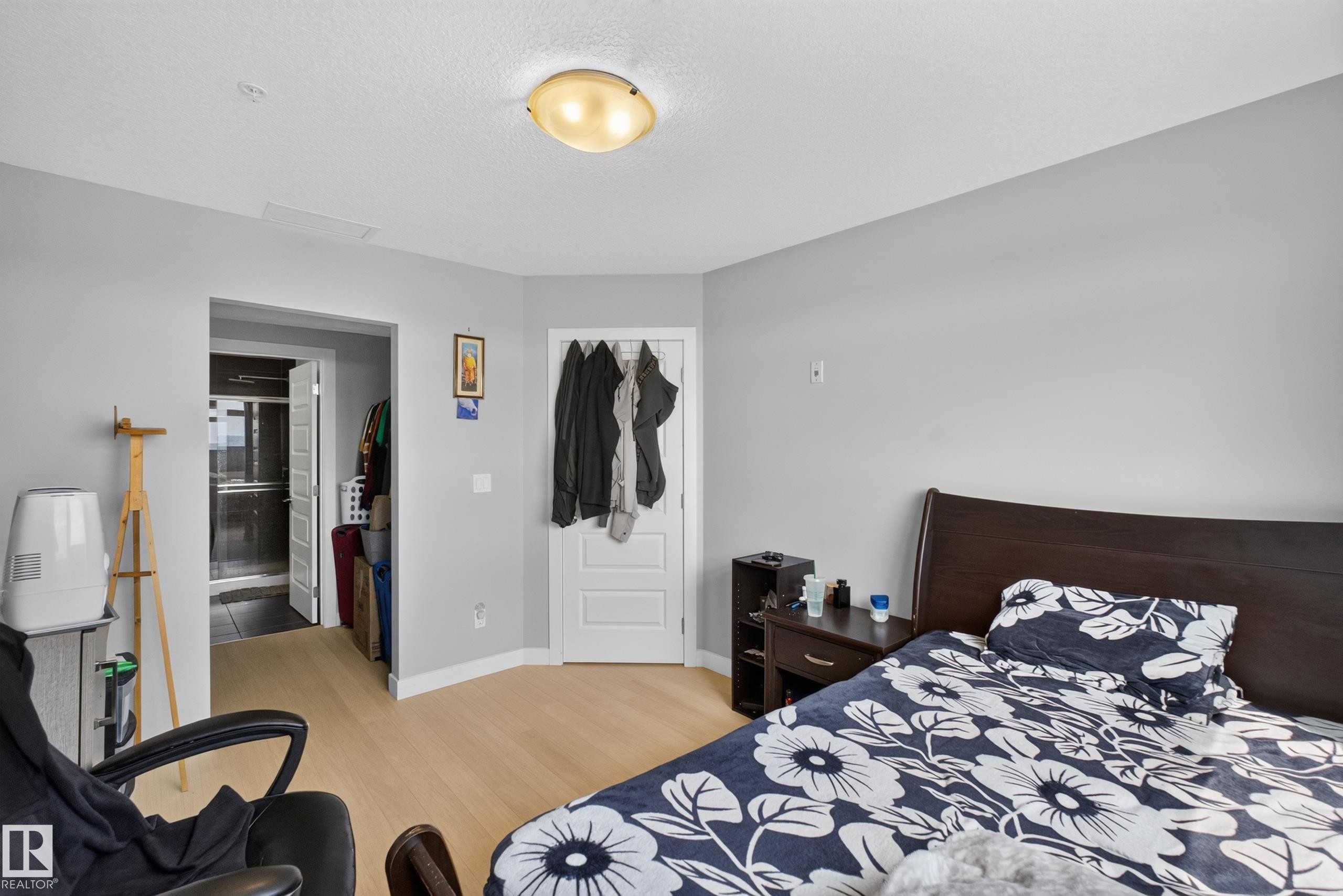 Spacious room featuring light wood-finish flooring and neutral gray walls - 706 5151 Windermere Boulevard, Edmonton, AB