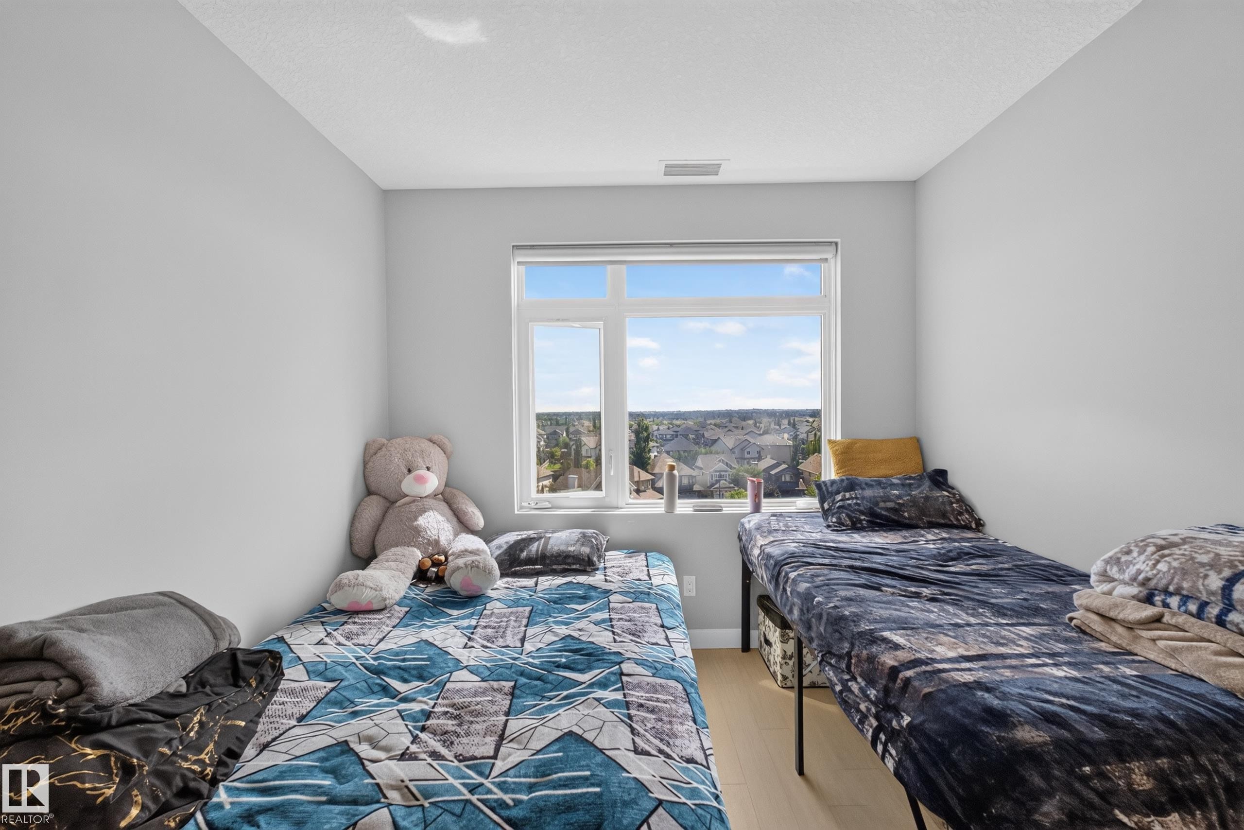 Light-toned walls with a single window providing natural light and neighborhood scenery - 706 5151 Windermere Boulevard, Edmonton, AB