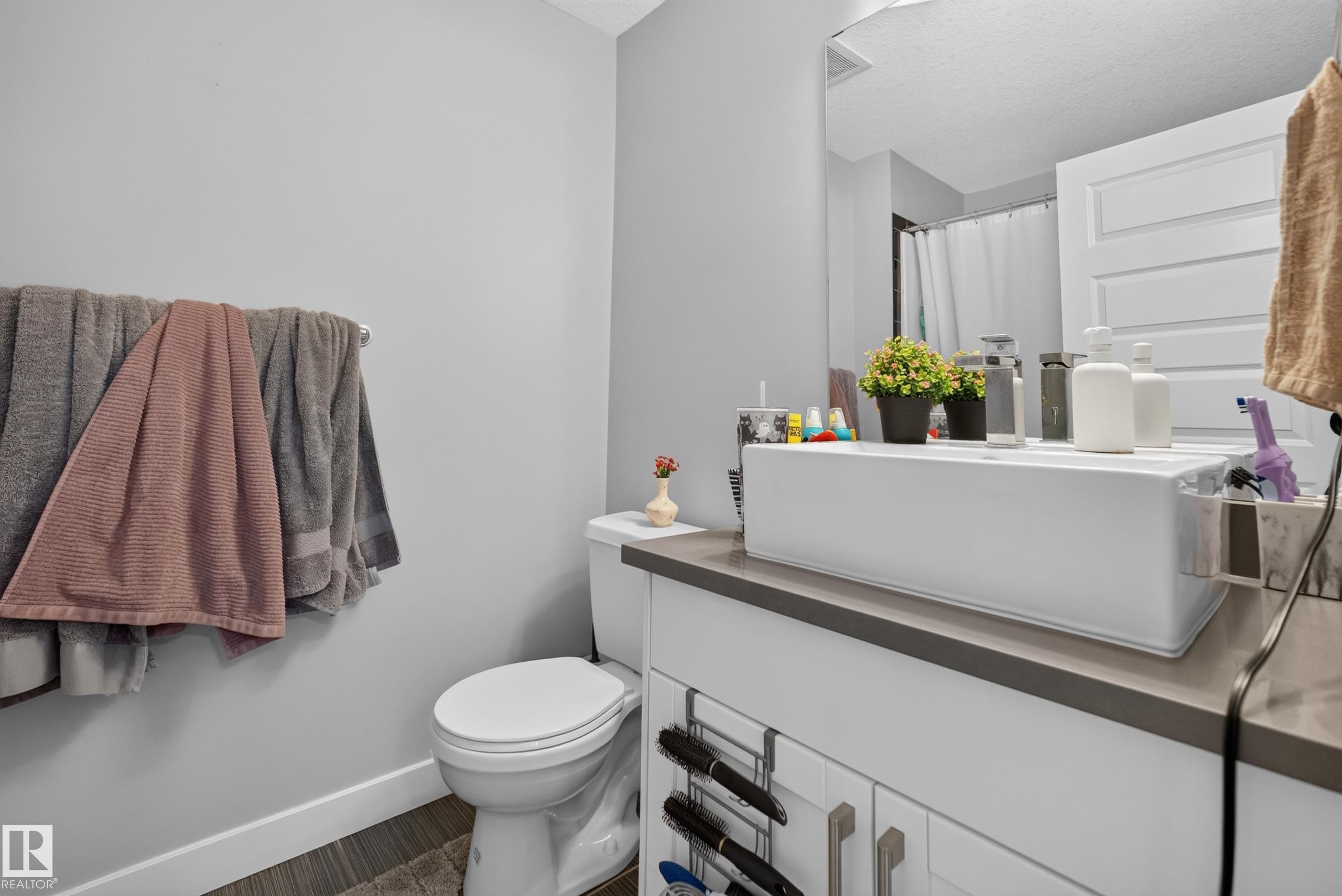 Bathroom vanity with a rectangular vessel sink, gray countertop, and white cabinetry featuring brushed nickel hardware - 706 5151 Windermere Boulevard, Edmonton, AB
