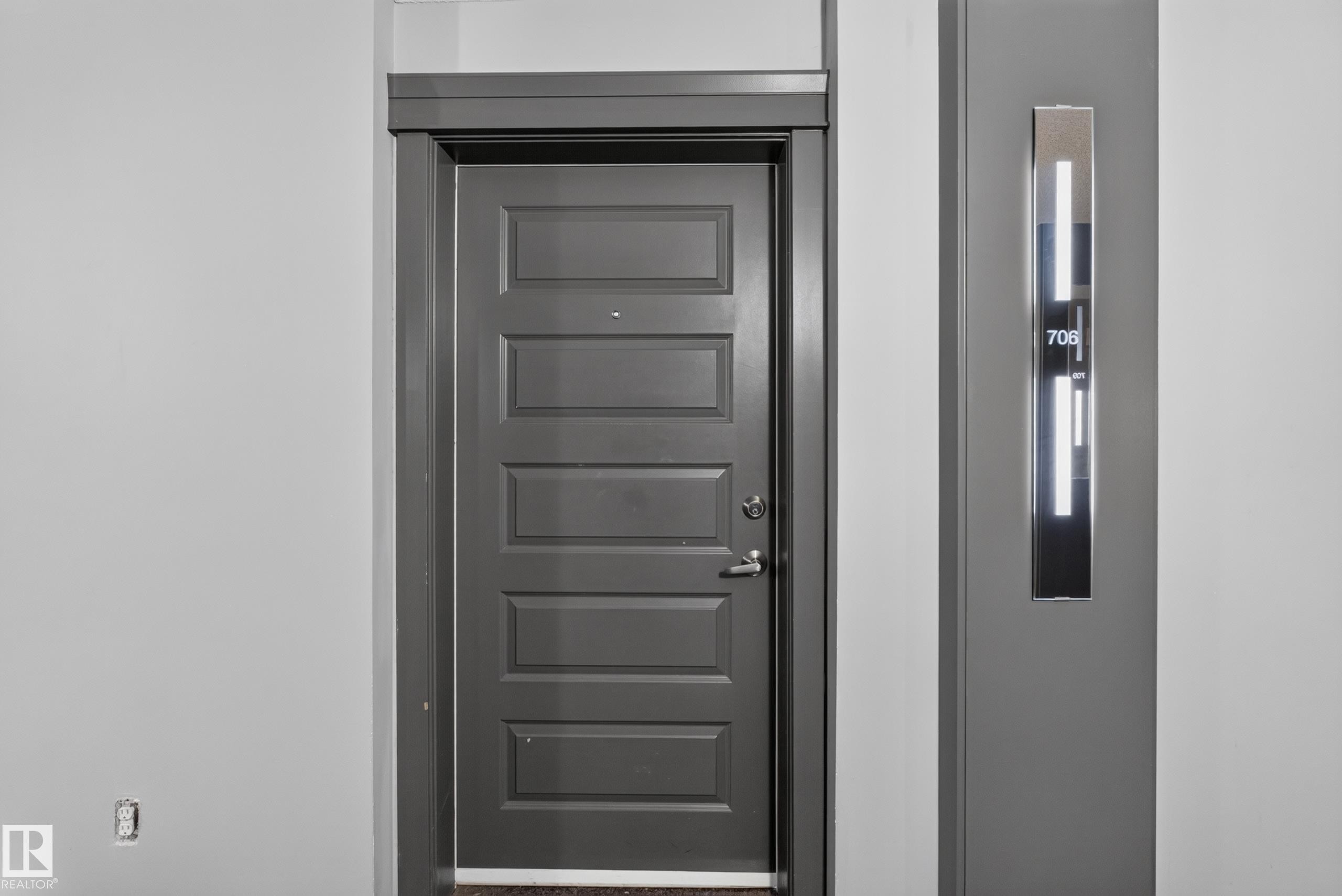 Panel-style entry door with modern hardware - 706 5151 Windermere Boulevard, Edmonton, AB