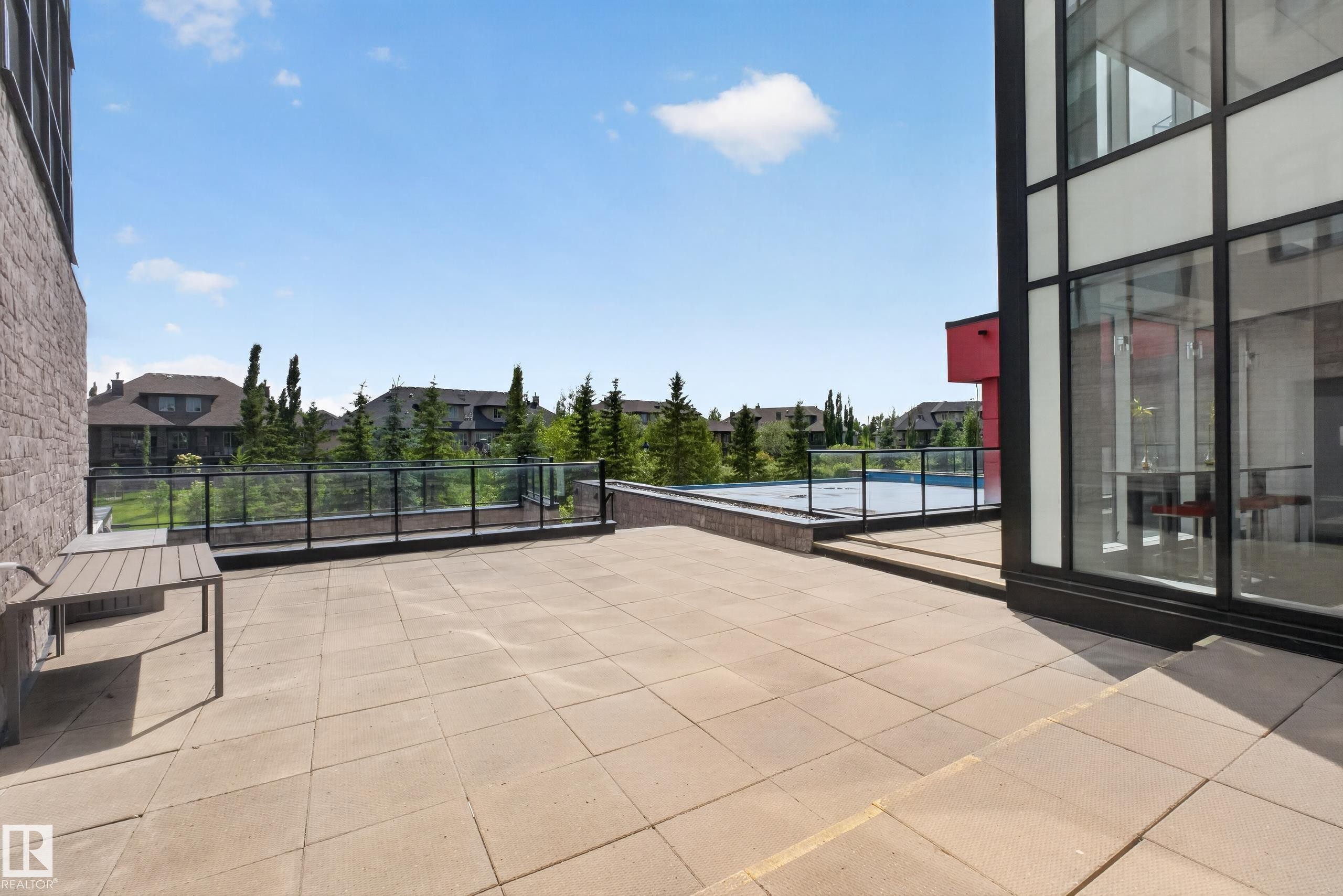 Spacious outdoor patio area featuring large format paver tiles and a glass panel railing system - 706 5151 Windermere Boulevard, Edmonton, AB