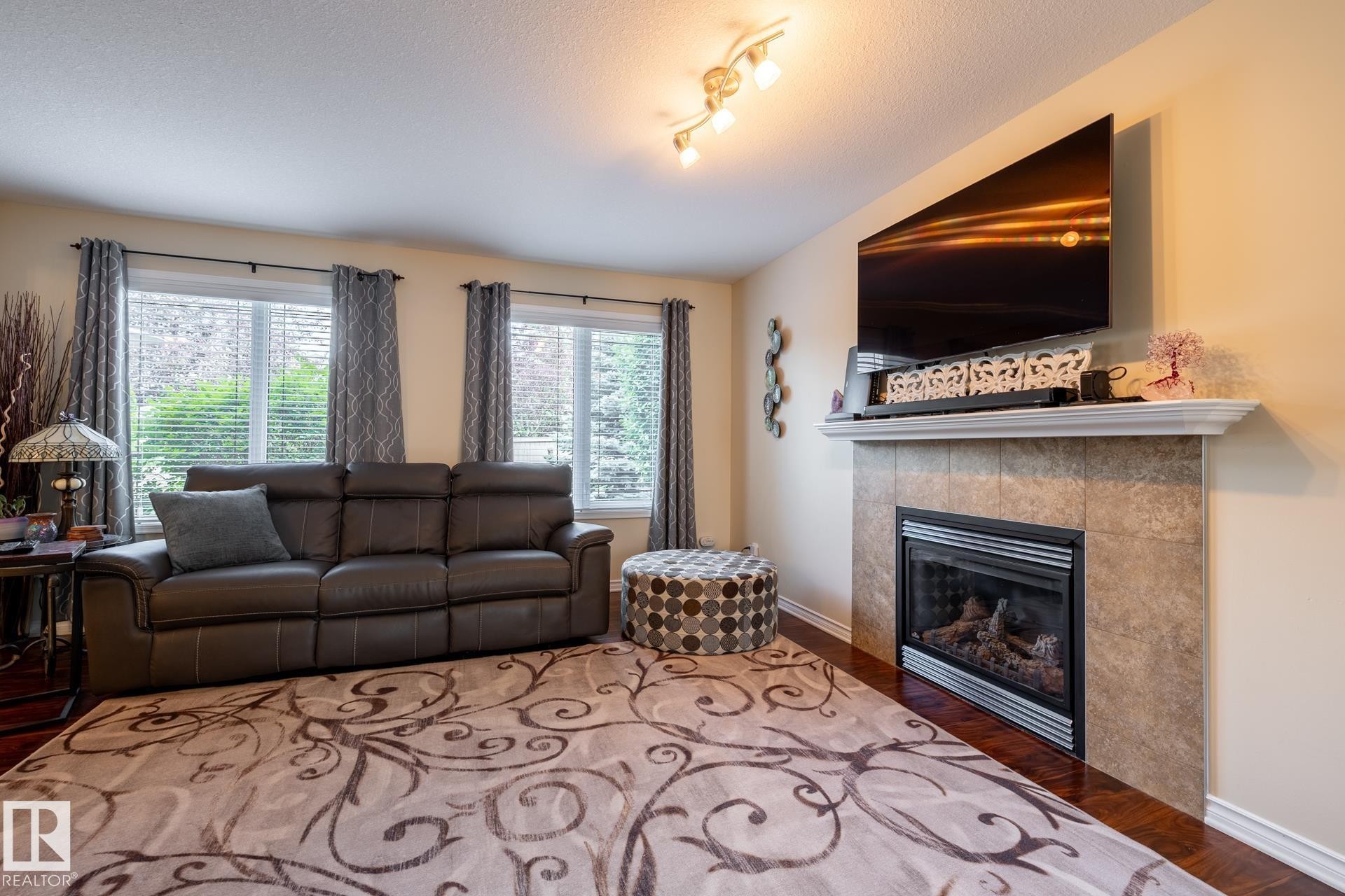 Living area featuring wood-finish flooring and track lighting - 5820 7 Avenue Sw, Edmonton, AB - Indoor Photo Showing Living Room With Fireplace