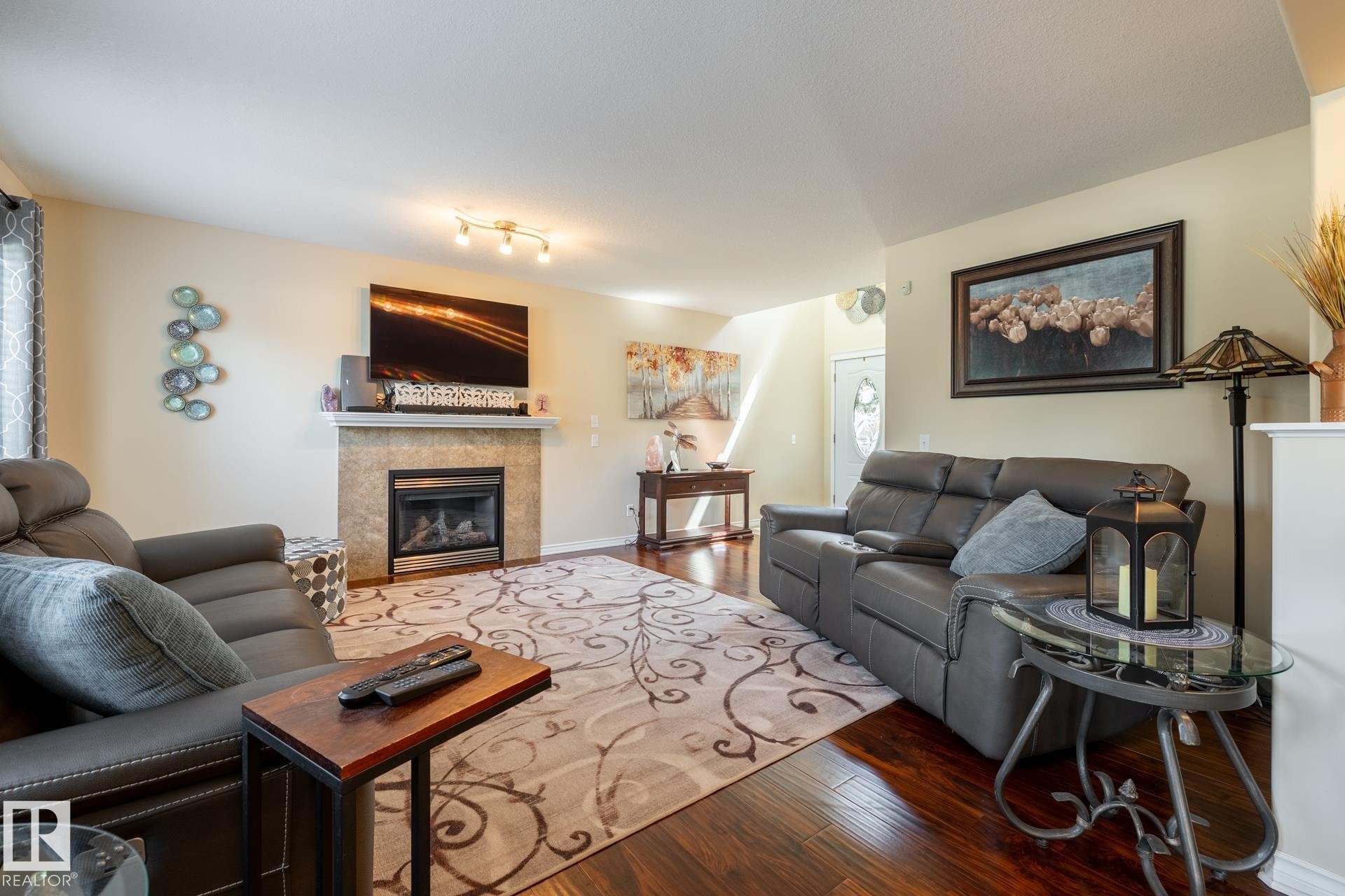 Living area featuring wood-finish flooring, a fireplace with a stone-tile surround, and a mantel - 5820 7 Avenue Sw, Edmonton, AB - Indoor Photo Showing Living Room With Fireplace