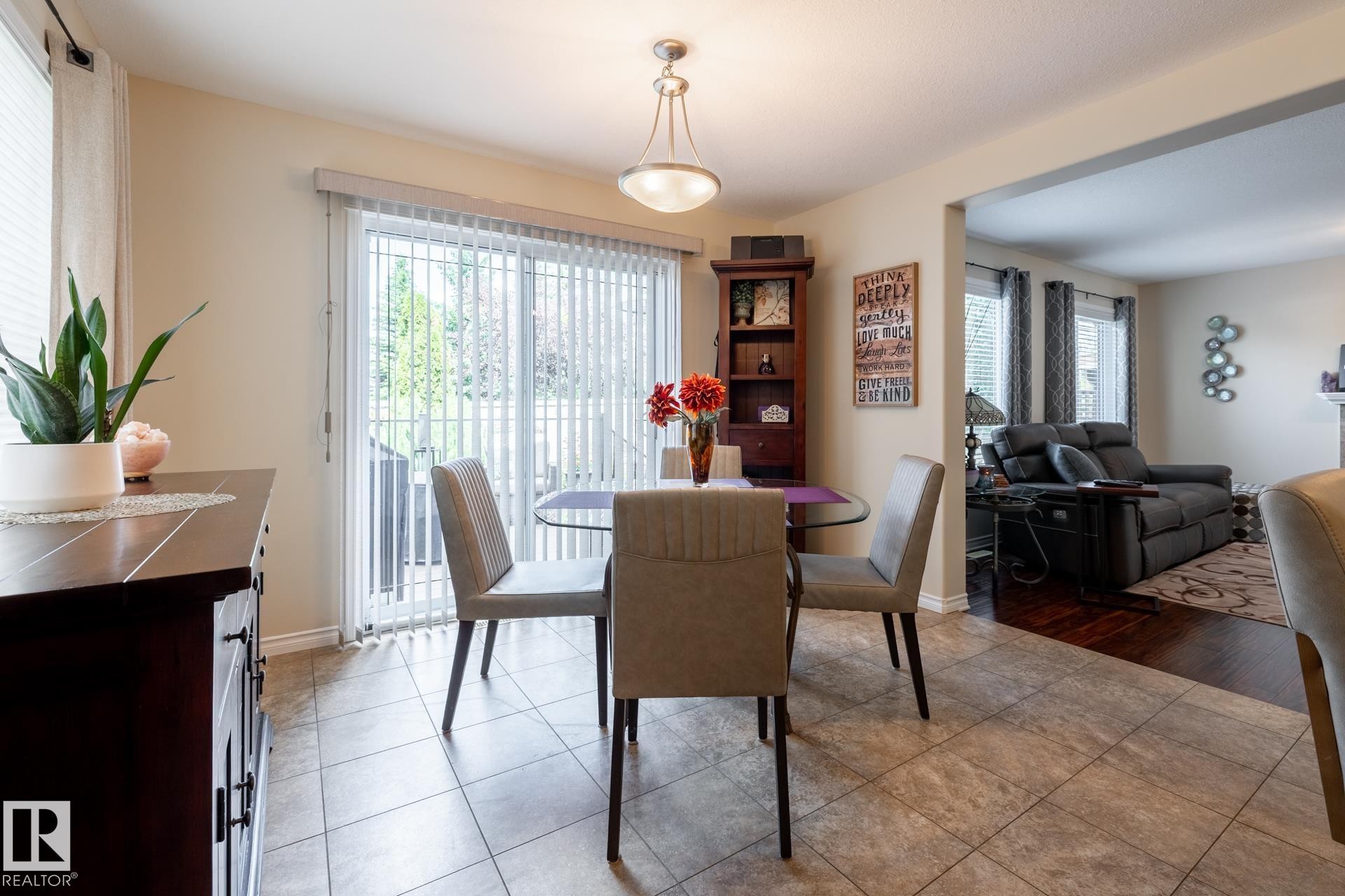 Dining area featuring neutral-toned tile flooring and a glass patio door with vertical blinds - 5820 7 Avenue Sw, Edmonton, AB - Indoor Photo Showing Dining Room