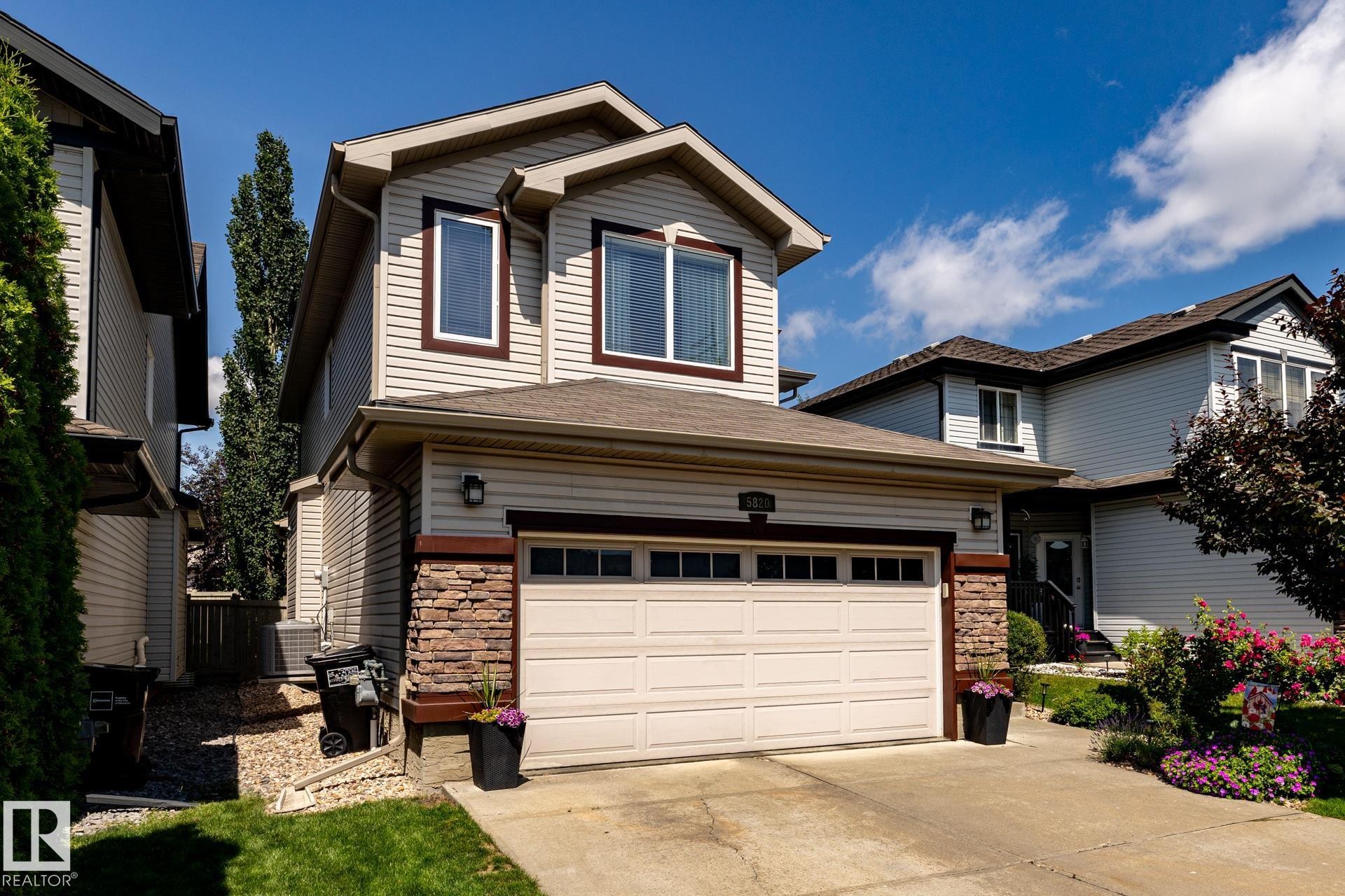 Two-story residence featuring light-colored siding with dark trim accents - 5820 7 Avenue Sw, Edmonton, AB - Outdoor