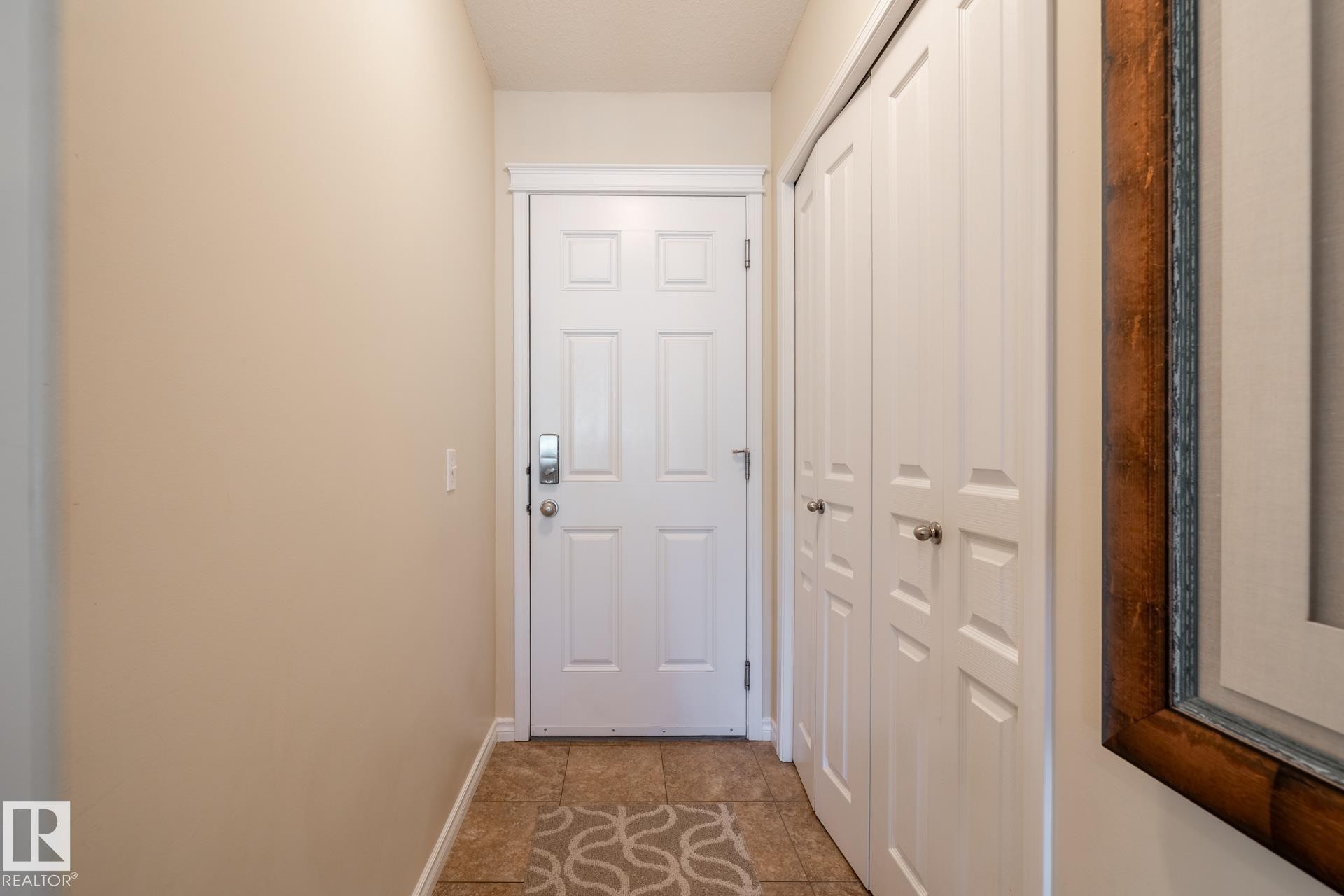 Entryway featuring a paneled door with modern hardware, ceramic tile flooring, and integrated bi-fold closet storage - 5820 7 Avenue Sw, Edmonton, AB - Indoor Photo Showing Other Room