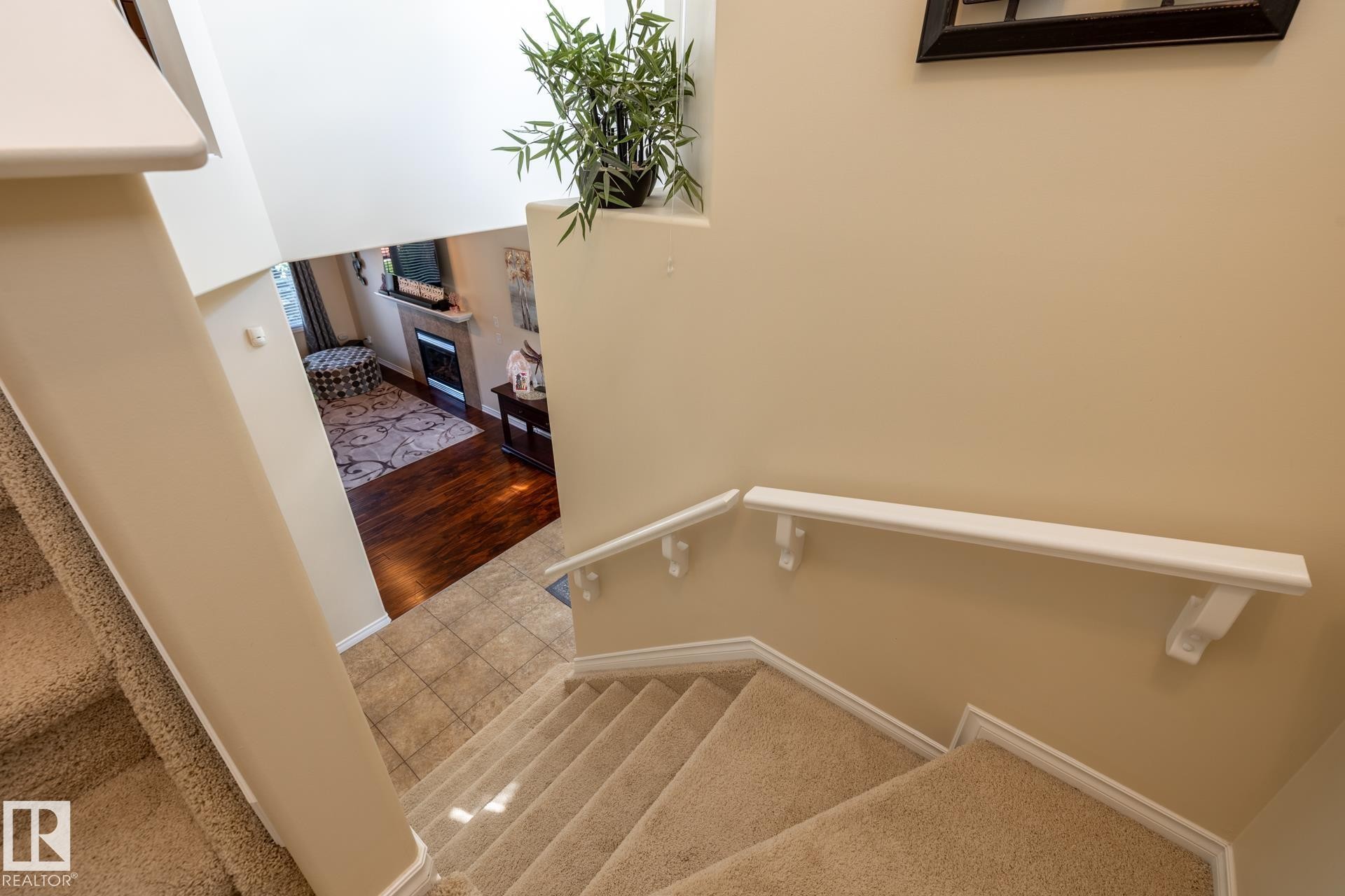 Carpeted staircase with white handrails and trim, overlooking a lower level with wood-finish flooring and a tiled entry - 5820 7 Avenue Sw, Edmonton, AB - Indoor Photo Showing Other Room
