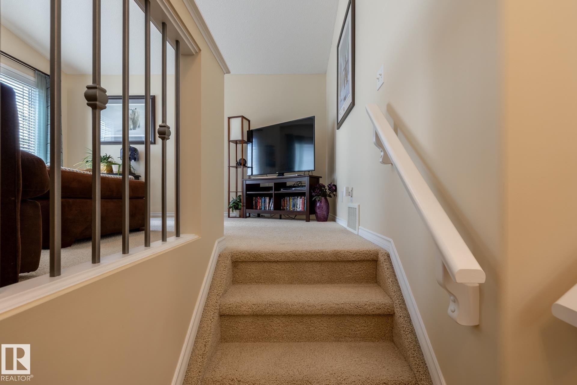 Carpeted staircase with white handrail and wrought iron balusters - 5820 7 Avenue Sw, Edmonton, AB - Indoor Photo Showing Other Room