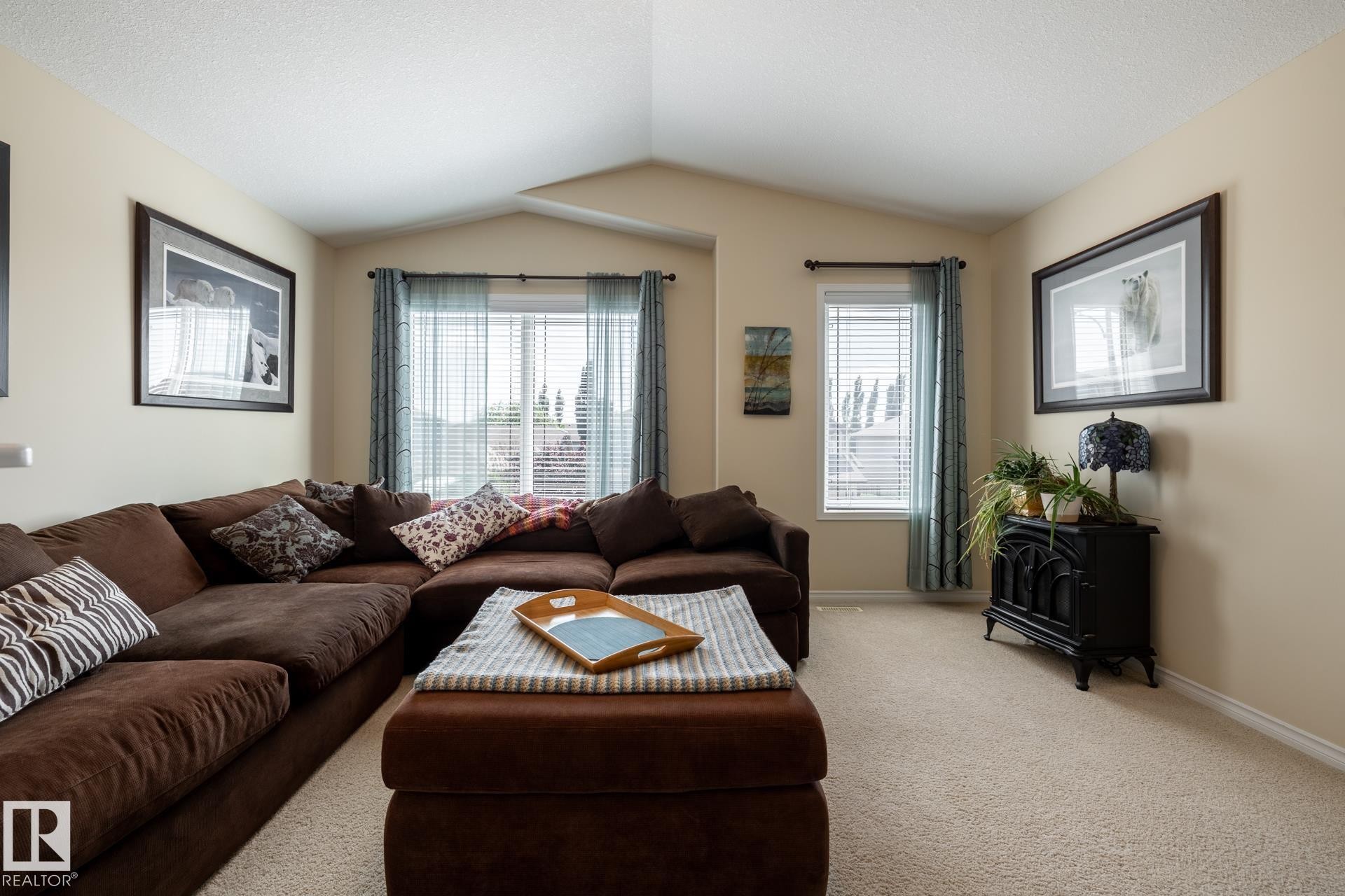 Spacious living area featuring neutral-toned walls, vaulted ceilings, and soft carpeting - 5820 7 Avenue Sw, Edmonton, AB - Indoor Photo Showing Living Room