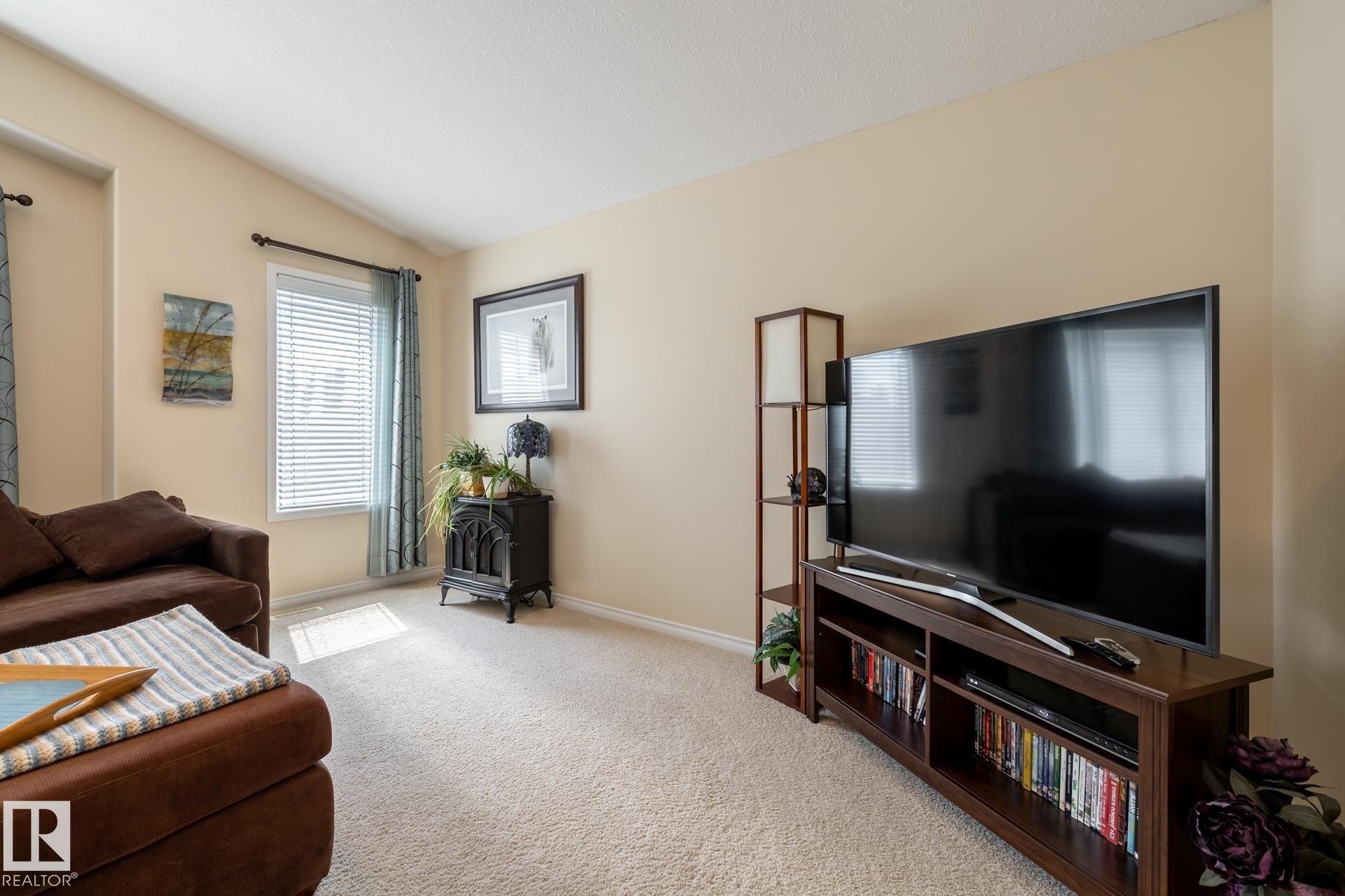 Carpeted living space featuring neutral-toned walls and a vaulted ceiling - 5820 7 Avenue Sw, Edmonton, AB - Indoor Photo Showing Living Room