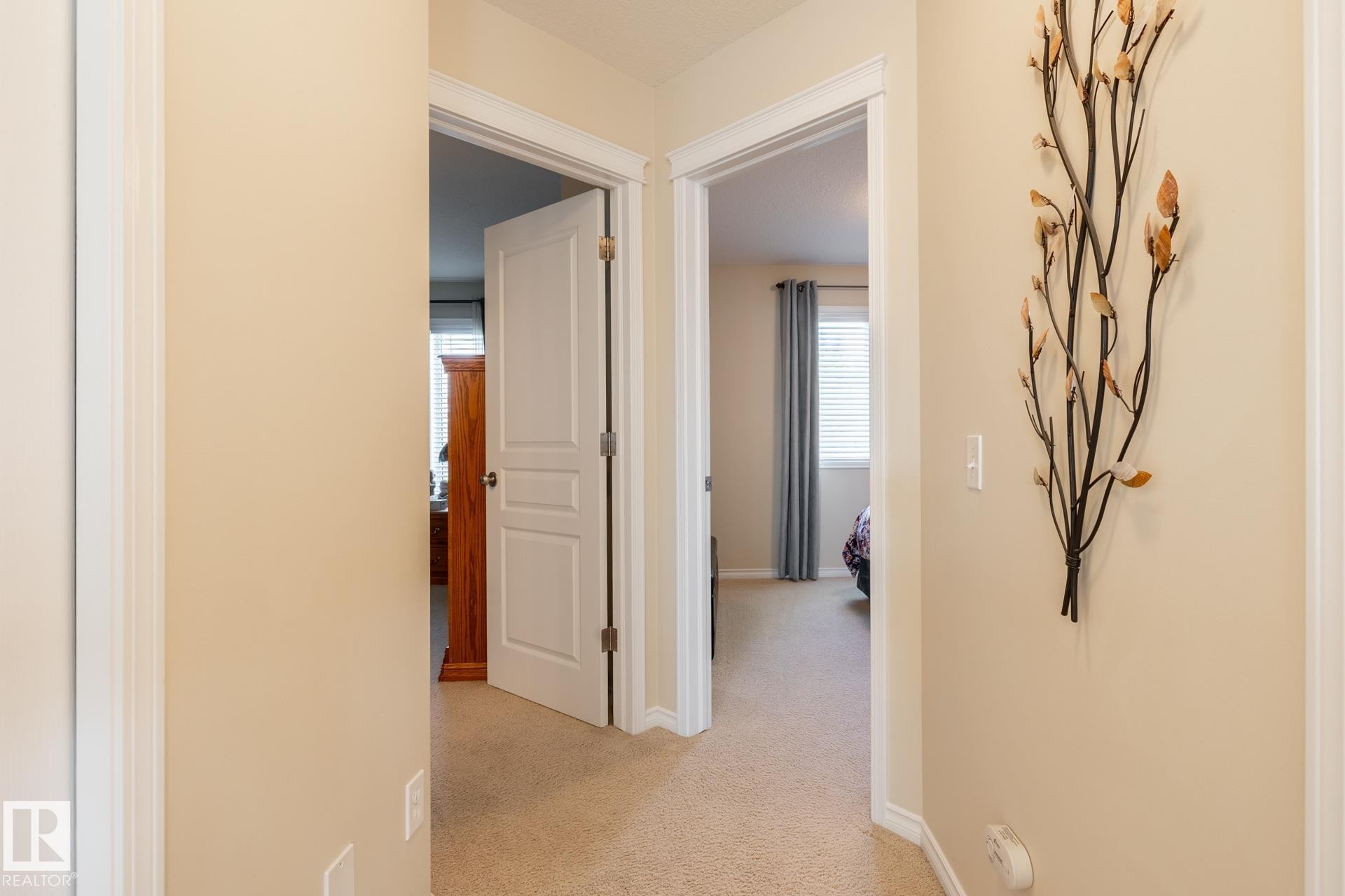 Neutral-toned hallway featuring carpet flooring, white trim, and two paneled doors opening into separate rooms - 5820 7 Avenue Sw, Edmonton, AB - Indoor Photo Showing Other Room
