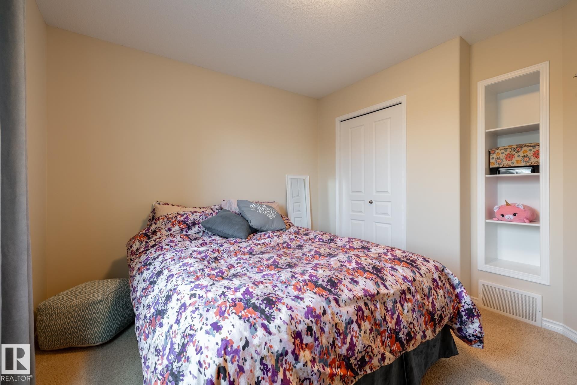 Bedroom featuring neutral wall paint, carpet flooring, a bifold closet door, and built-in shelving - 5820 7 Avenue Sw, Edmonton, AB - Indoor Photo Showing Bedroom