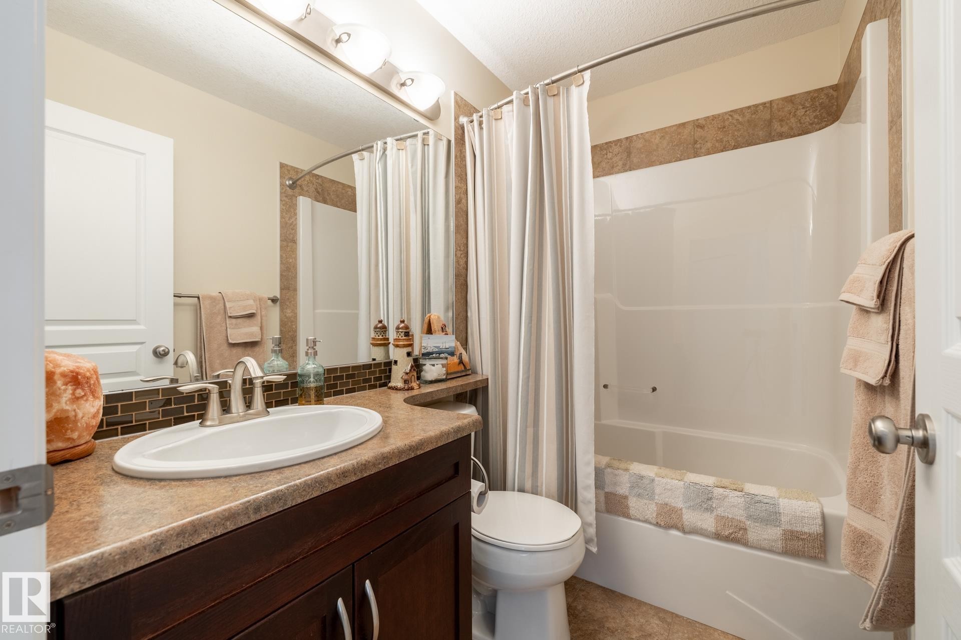 Bathroom featuring a single vanity with a laminate countertop, undermount sink, and dark wood-finish cabinetry - 5820 7 Avenue Sw, Edmonton, AB - Indoor Photo Showing Bathroom