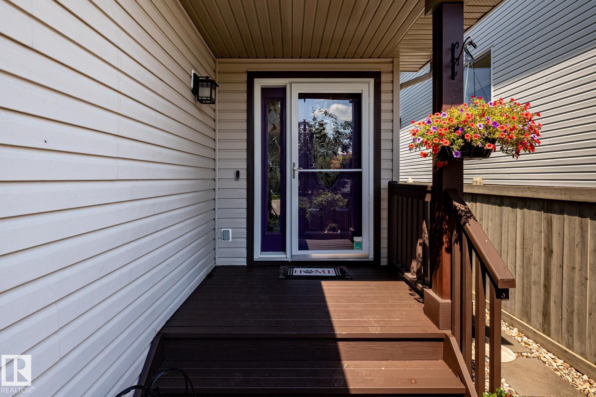 Front entry porch with dark wood-finish decking and railing - 5820 7 Avenue Sw, Edmonton, AB - Outdoor With Deck Patio Veranda With Exterior