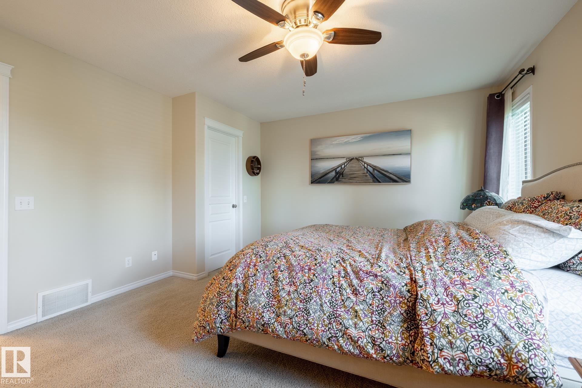Carpeted room featuring a ceiling fan with light fixture, neutral wall paint, and white trim - 5820 7 Avenue Sw, Edmonton, AB - Indoor Photo Showing Bedroom