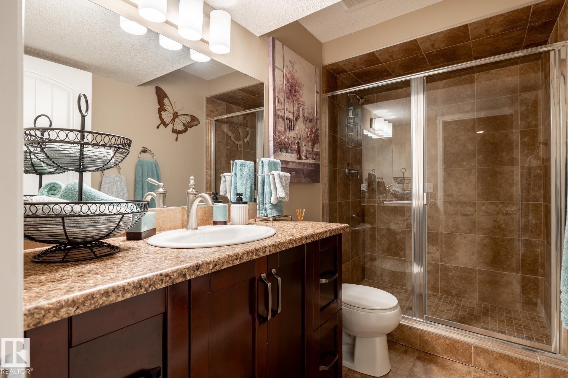 Bathroom featuring a glass-enclosed shower, a vanity with a countertop, an undermount sink, a chrome faucet, and a wall-mounted light fixture - 5820 7 Avenue Sw, Edmonton, AB - Indoor Photo Showing Bathroom